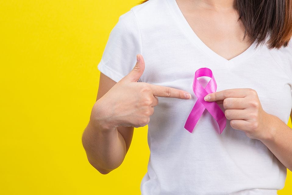 Breast cancer month, a woman in a white T-shirt with a satin pink ribbon on her chest, a symbol for breast cancer awareness campaign in October