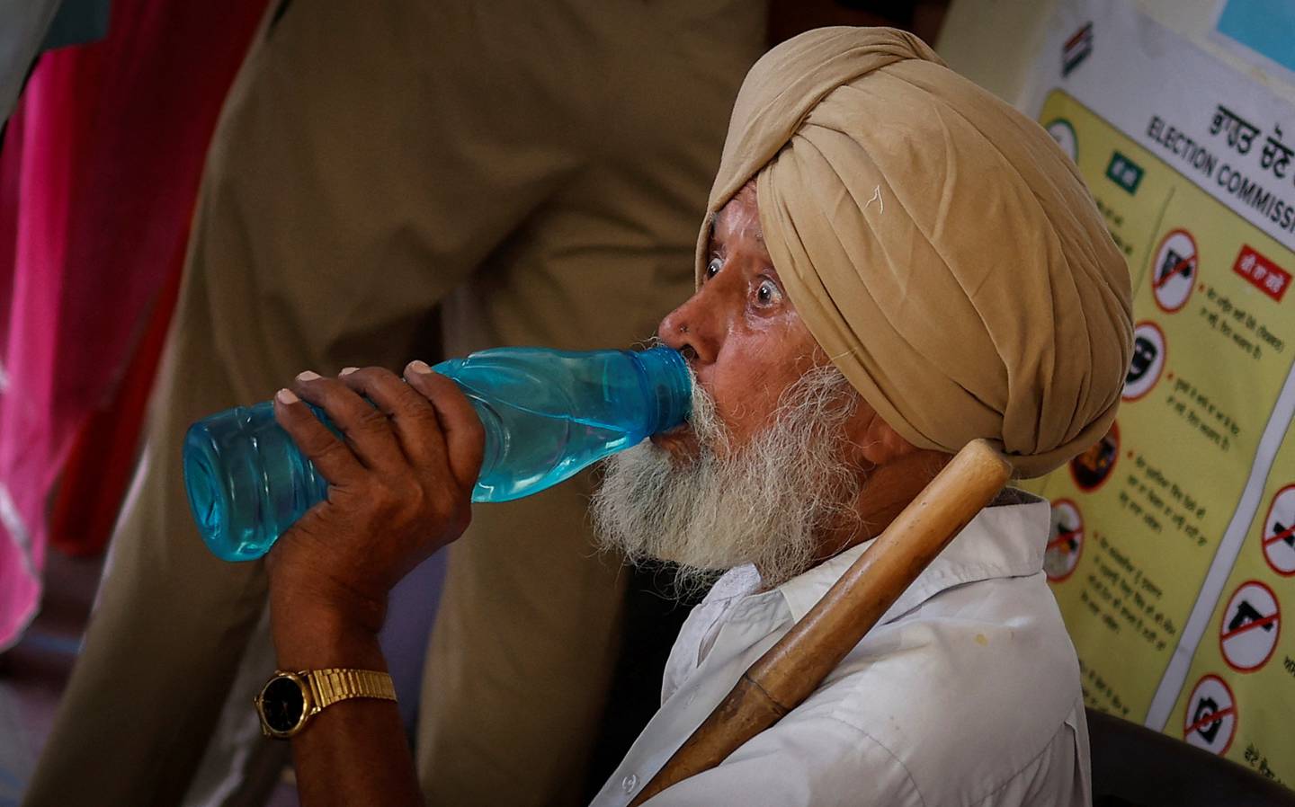 Un hombre bebe agua mientras espera fuera de una cabina para depositar su voto en un colegio electoral durante la séptima y última fase de las elecciones generales, en el distrito de Faridkot, Punjab, India. 1 de junio de 2024. REUTERS/Adnan Abidi
