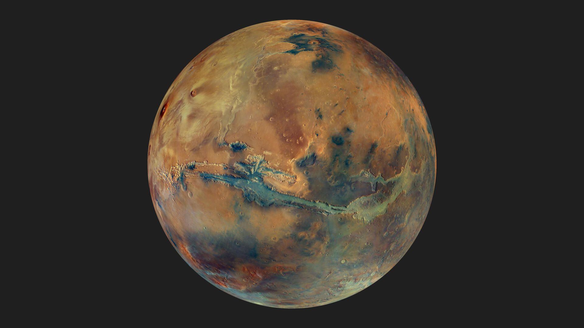Imagen compuesta por un mosaico de imágenes que muestra el globo terráqueo de Marte sobre un fondo oscuro. El disco del planeta presenta manchas amarillas, naranjas, azules y verdes, todas ellas con un tono gris apagado, que representa la composición variable de la superficie. Cedida por ESA/DLR/FU Berlin/G. Michael, CC BY-SA 3.0 IGO
