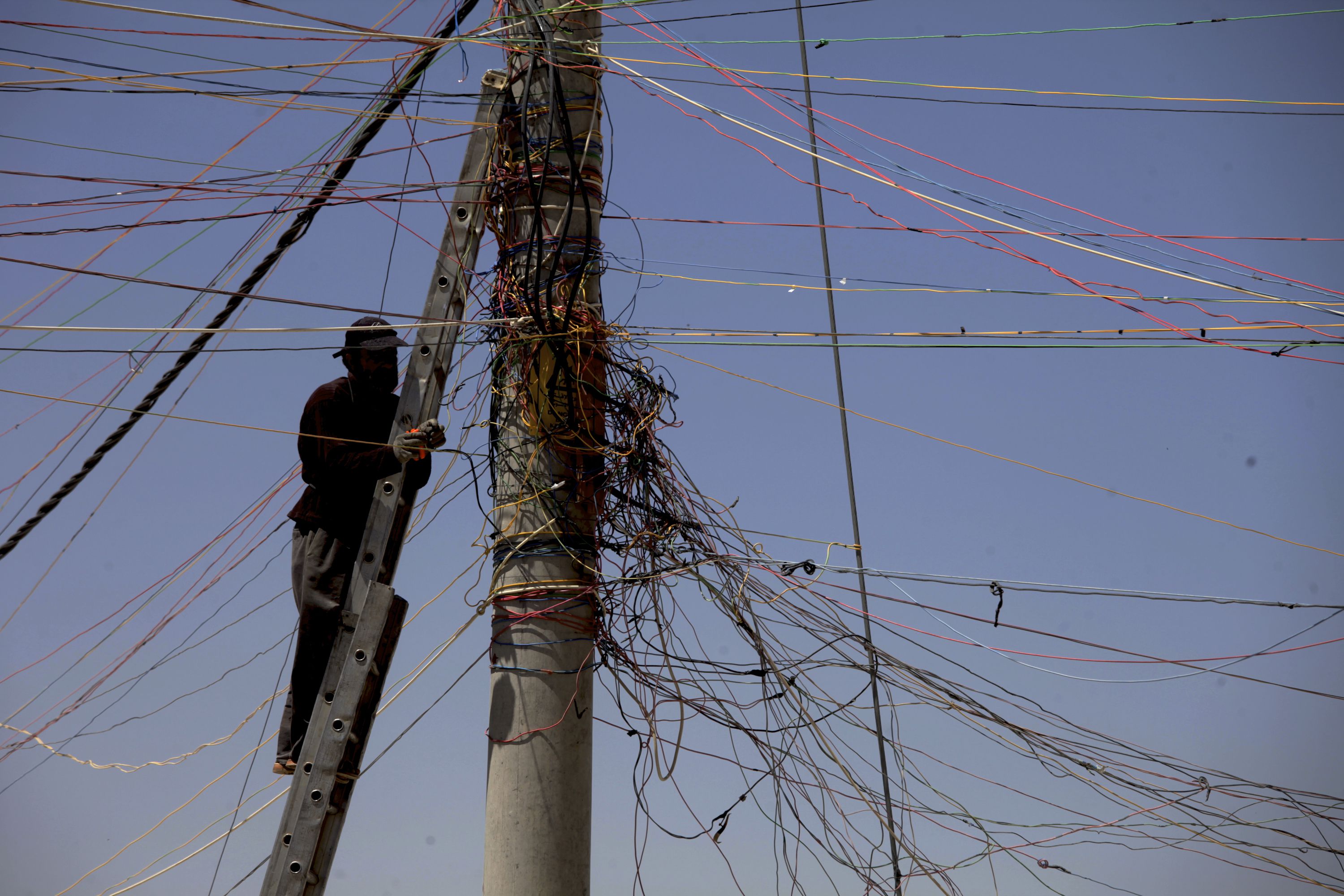 A man tries to connect his store with electricity from the main electricity pole at the Zaatari Refugee Camp, in Mafraq, Jordan, Tuesday April 22, 2014. An estimated 104,494 refugees reside in the sprawling Zaatari refugee camp, according to the United Nations High Commissioner for Refugees (UNHCR), with the majority of the population coming from the Daara Governorate in southwest Syria. (AP Photo/Mohammad Hannon)