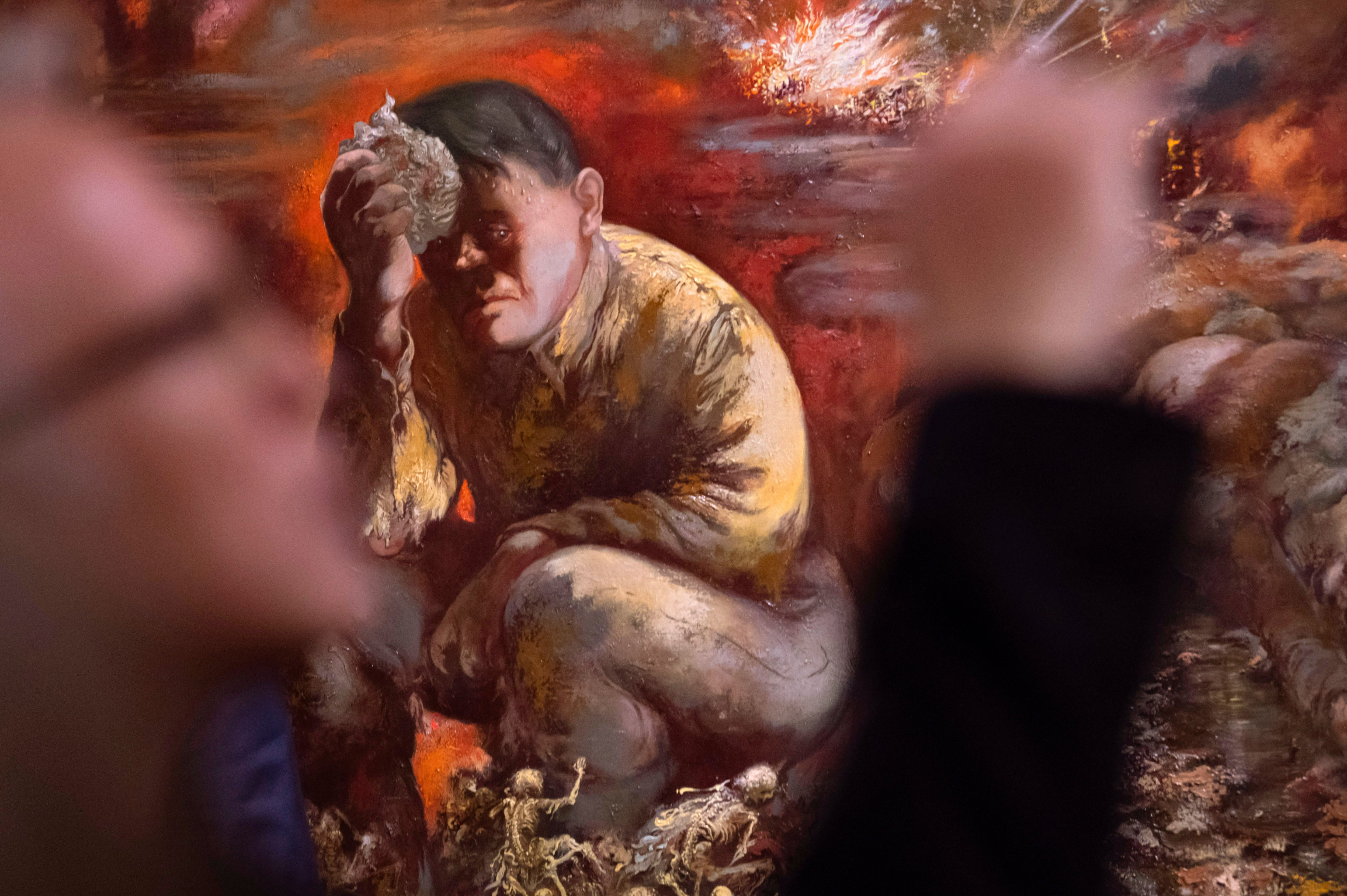 Un hombre toma una foto de la pintura "Caín o Hitler en el infierno" de George Grosz durante una presentación a la prensa en el Museo Histórico Alemán, en Berlín, el martes 4 de febrero del 2020. La obra de 1944 forma parte de una nueva colección permanente en el museo. (AP Foto/Jens Meyer)