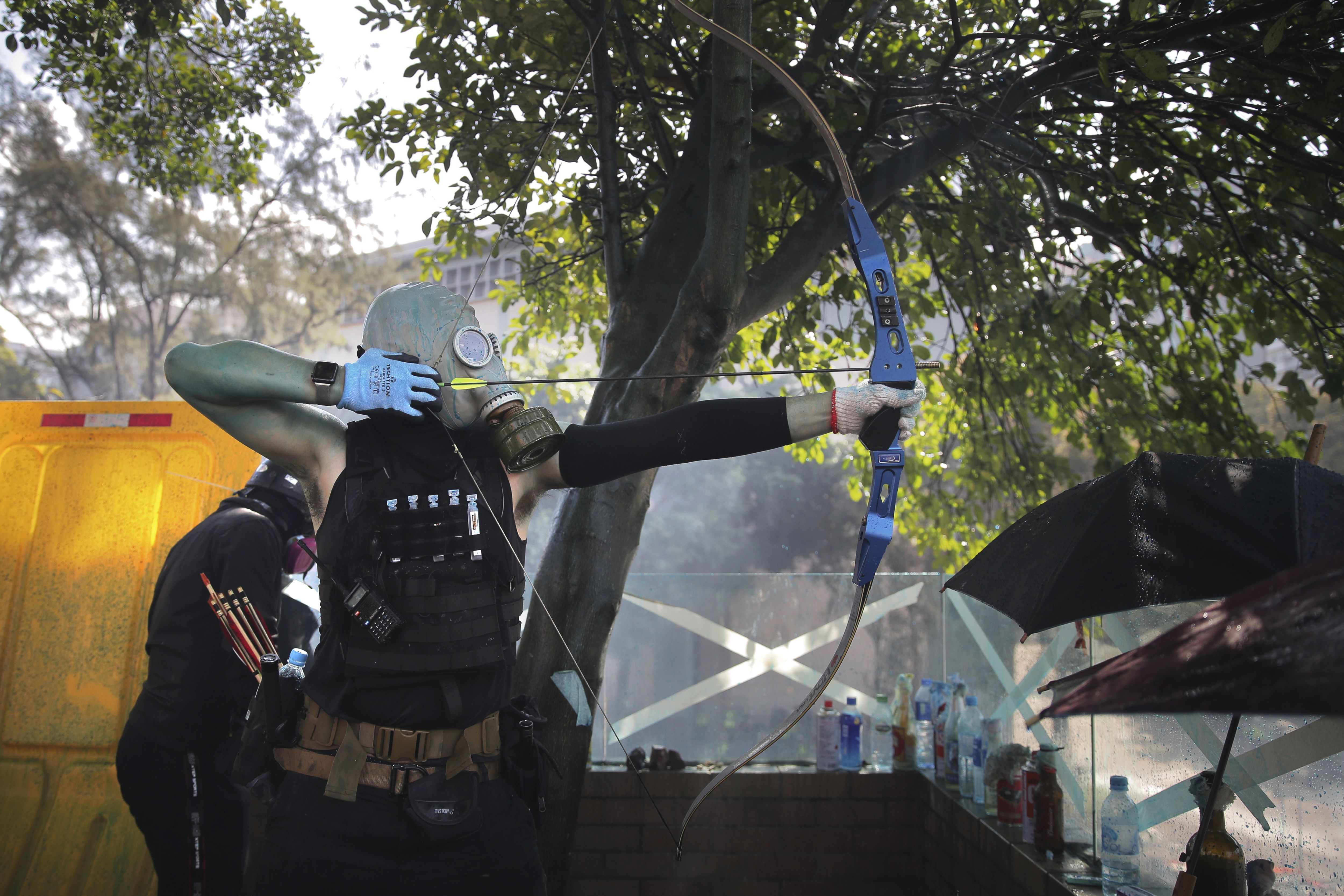 Un manifestante se prepara para disparar una flecha durante choques con la policía en la Universidad Politécnica de Hong Kong, el domingo 17 de noviembre de 2019. (AP Foto/Kin Cheung)