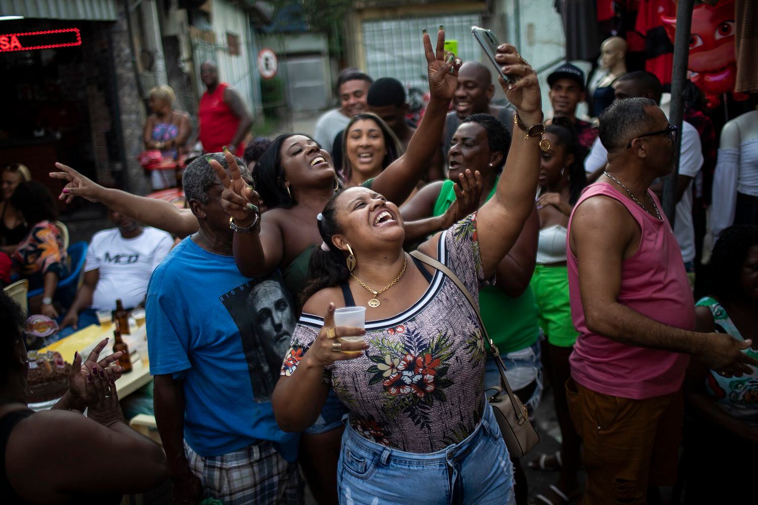 Michele Pereira se toma una selfie con su familia mientras celebran el cumpleaños de un pariente en un evento de samba en Vila Vintem, Rio de Janeiro, Brasil, el sábado 23 de mayo de 2021. La nueva versión de Anitta del clásico de la bossa nova "La chica de Ipanema" ofrece una actualización de las mujeres de Río respecto a la original de los años 60. (AP Foto/Bruna Prado)