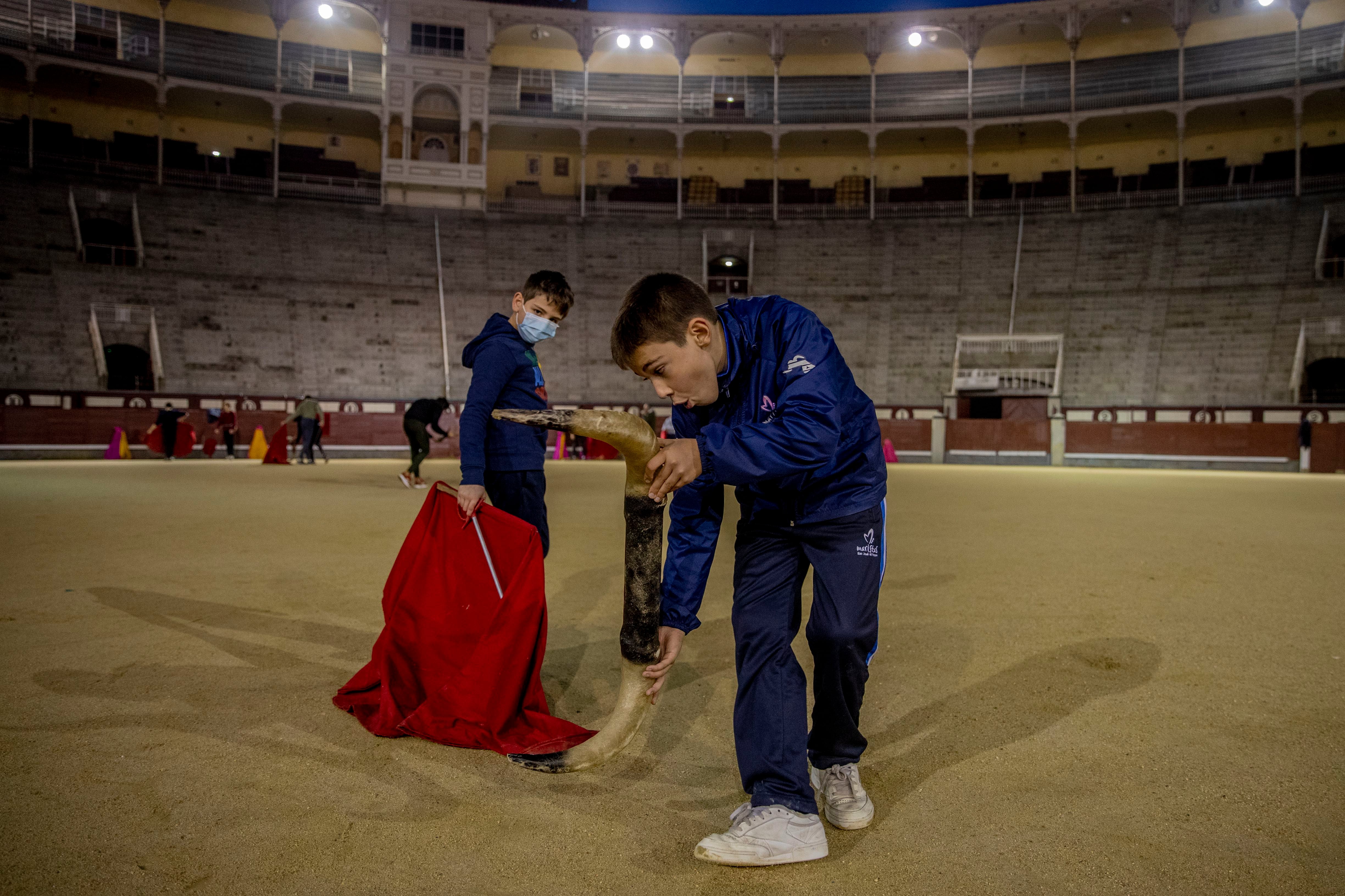 Nicolás Sanz Luna, de 10 años (der) ensaya los movimientos de un toro con cuernos de plástico en la escuela taurina de Las Ventas, en Madrid, el 22 de diciembre del 2020. La escuela cuenta con alumnos de hasta nueve años, que aprenden la danza mortal entre matador y toro. (AP Photo/Manu Fernández)