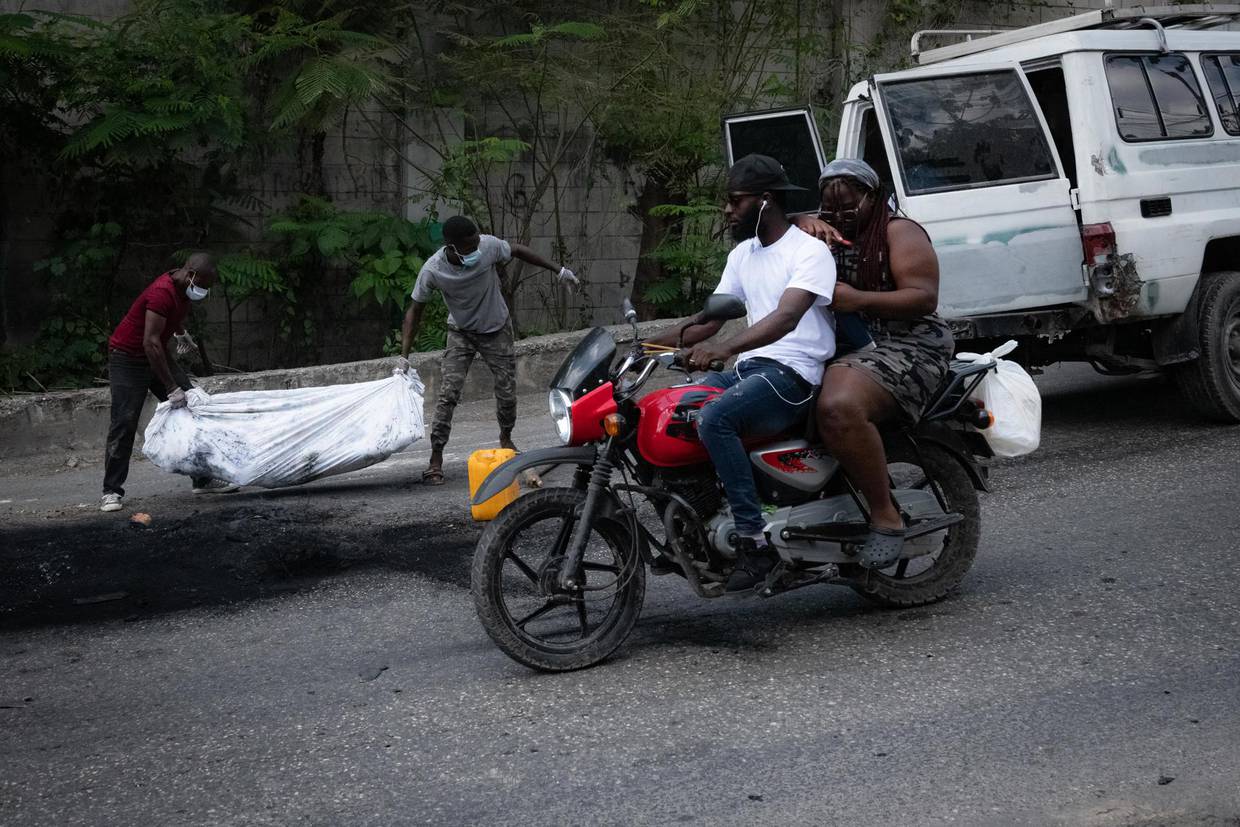Fotografía de archivo de dos hombres cargan el cuerpo de una persona en Puerto Príncipe (Haití). EFE/ Johnson Sabin
