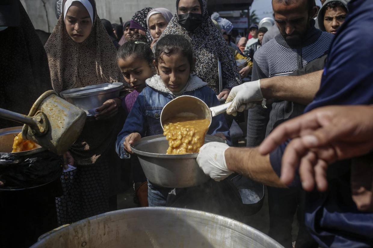 Niños palestinos desplazados reciben alimentos proporcionados por donantes árabes y palestinos en la ciudad de Deir al Balah, al sur de la Franja de Gaza, el 24 de febrero de 2024. | AP