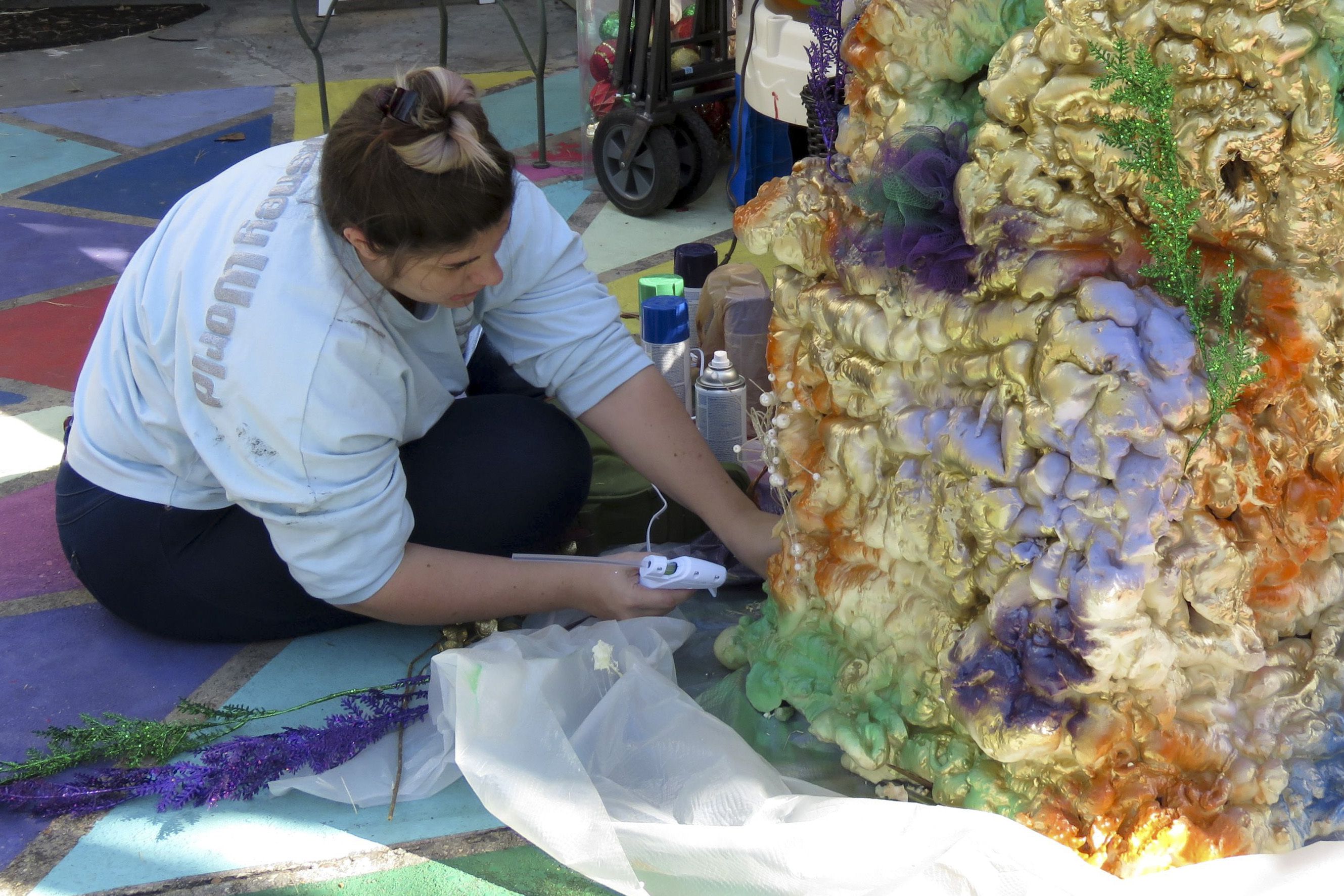 Carley Sercovich trabaja en un arrecife de coral hecho con cajas y pintura en aerosol mientras decora su casa como carroza de Mardi Gras en el barrio de Algiers Point, en Nueva Orleans, el viernes 15 de enero de 2021. Con la cancelación de los tradicionales desfiles de Mardi Gras debido a la pandemia de coronavirus, miles alrededor de la ciudad han decorado sus casas para celebrar el Carnaval. (AP Foto/Janet McConnaughey)