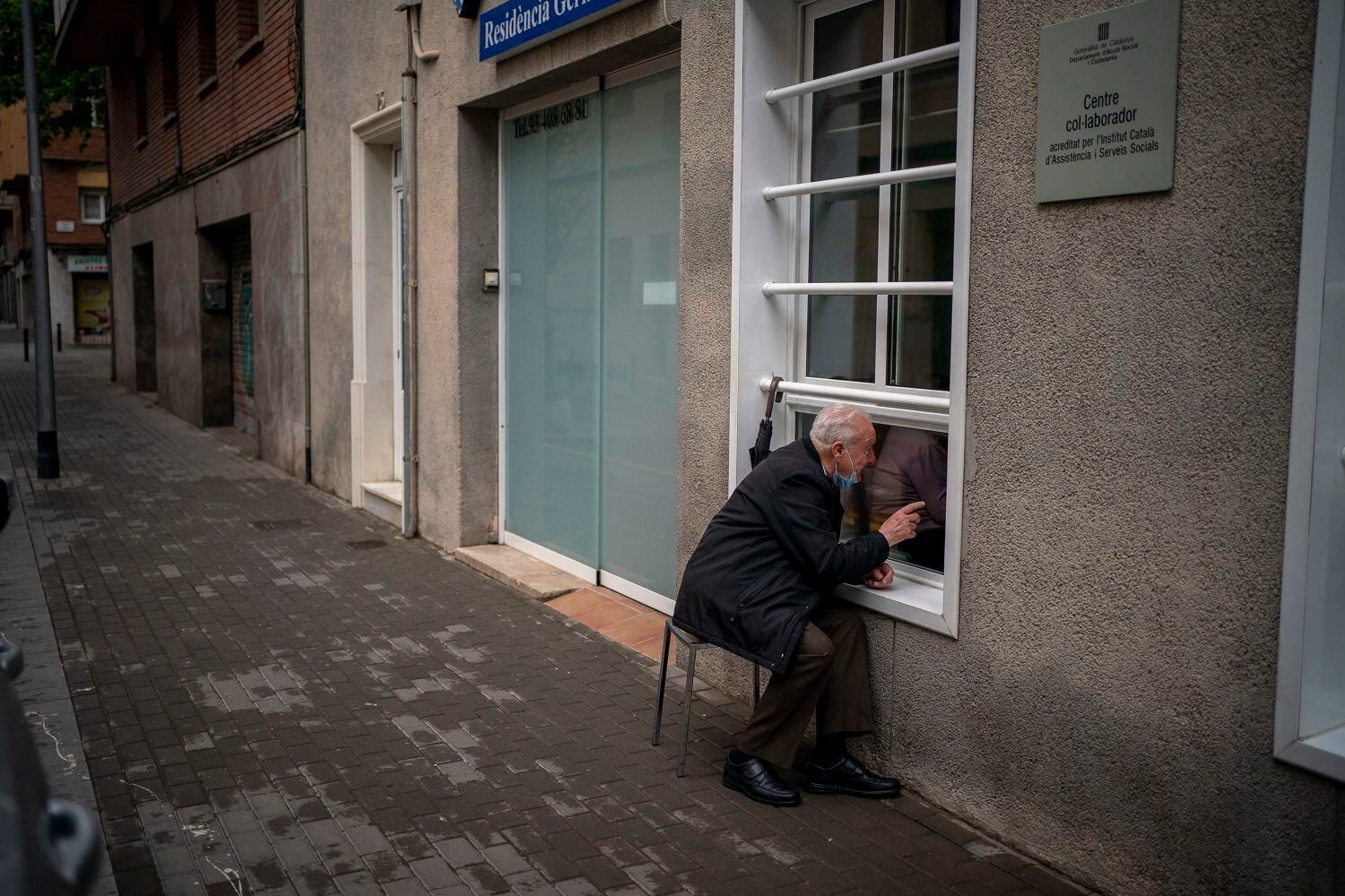 Xavier Antó, de 90 años, habla con su esposa Carmen Panzano, de 92, a través de una ventana en el asilo donde ella vive en Barcelona, España, el 21 de abril de 2021. La casa de ancianos tomó estas medidas para proteger a sus residentes del coronavirus. (AP Foto/Emilio Morenatti)