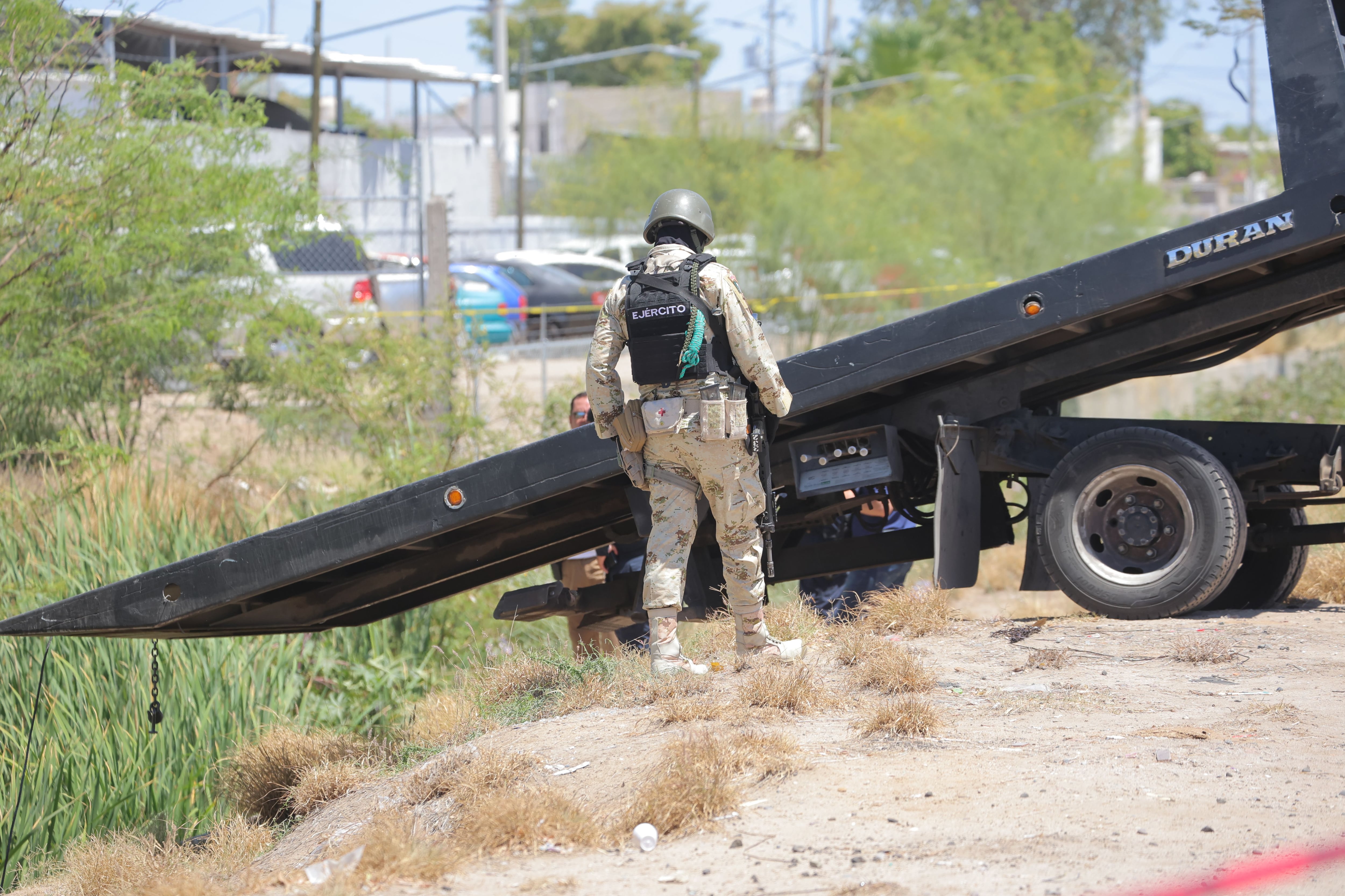 Un elemento del Ejército Mexicano observa cómo una grúa se dispone
a sacar el vehículo que cayó al canal del bulevar Lázaro Cárdenas, luego
que su conductor fuera lesionado a balazos.