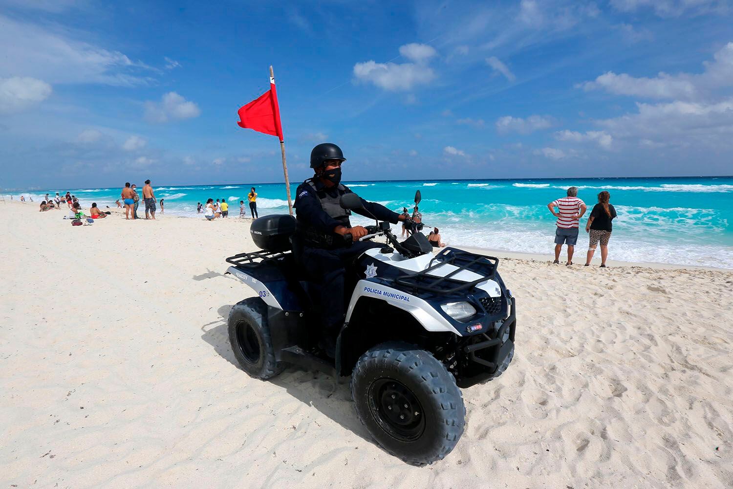Un policía patrulla una playa con algunos turistas hoy, en Cancún (México). EFE/Alonso Cupul
