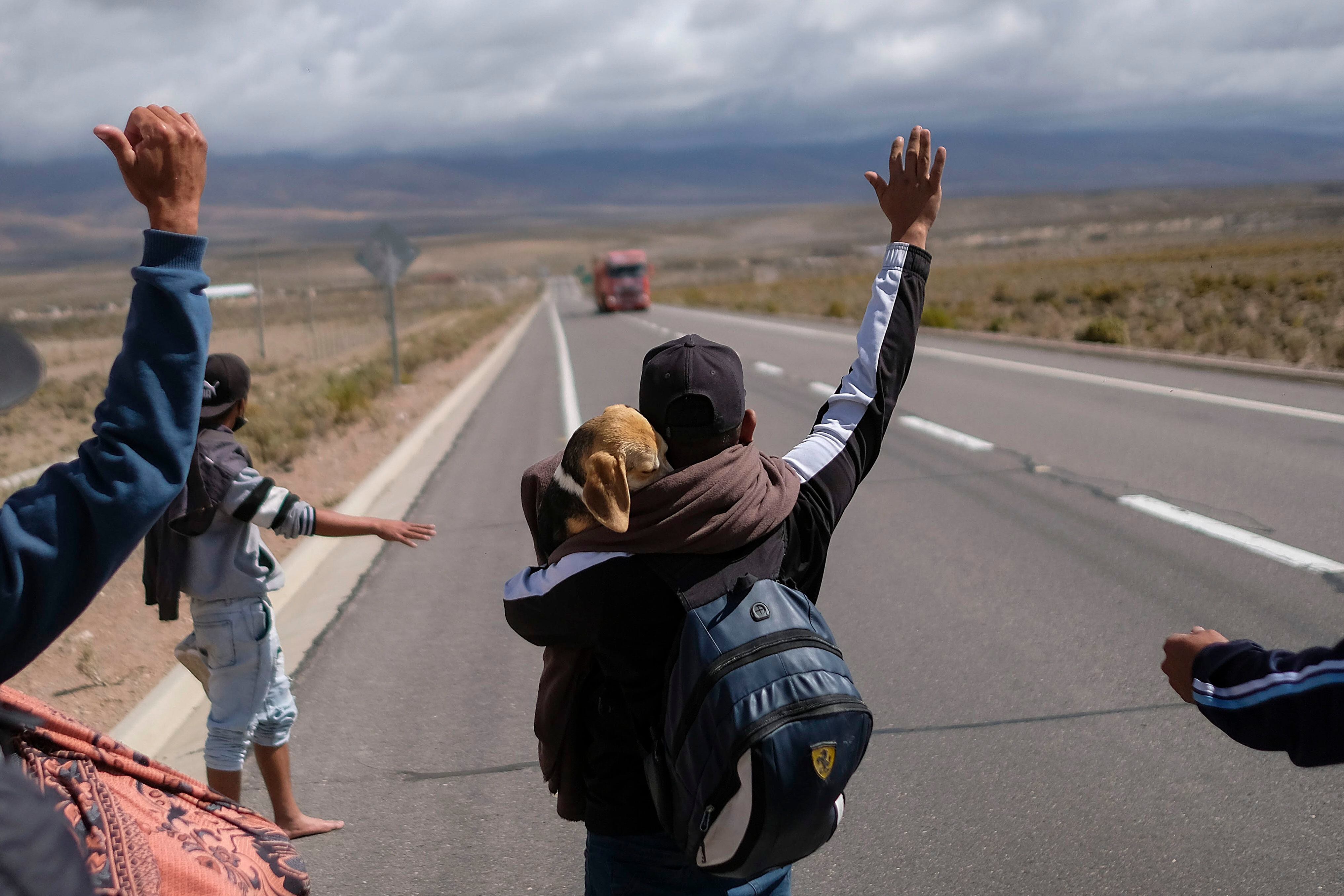 A Venezuelan migrant holds his dog as he tries to hitch a ride to Iquique, on a highway between Huara and Colchane, Chile, Friday, Dec. 10, 2021. (AP Photo/Matias Delacroix)