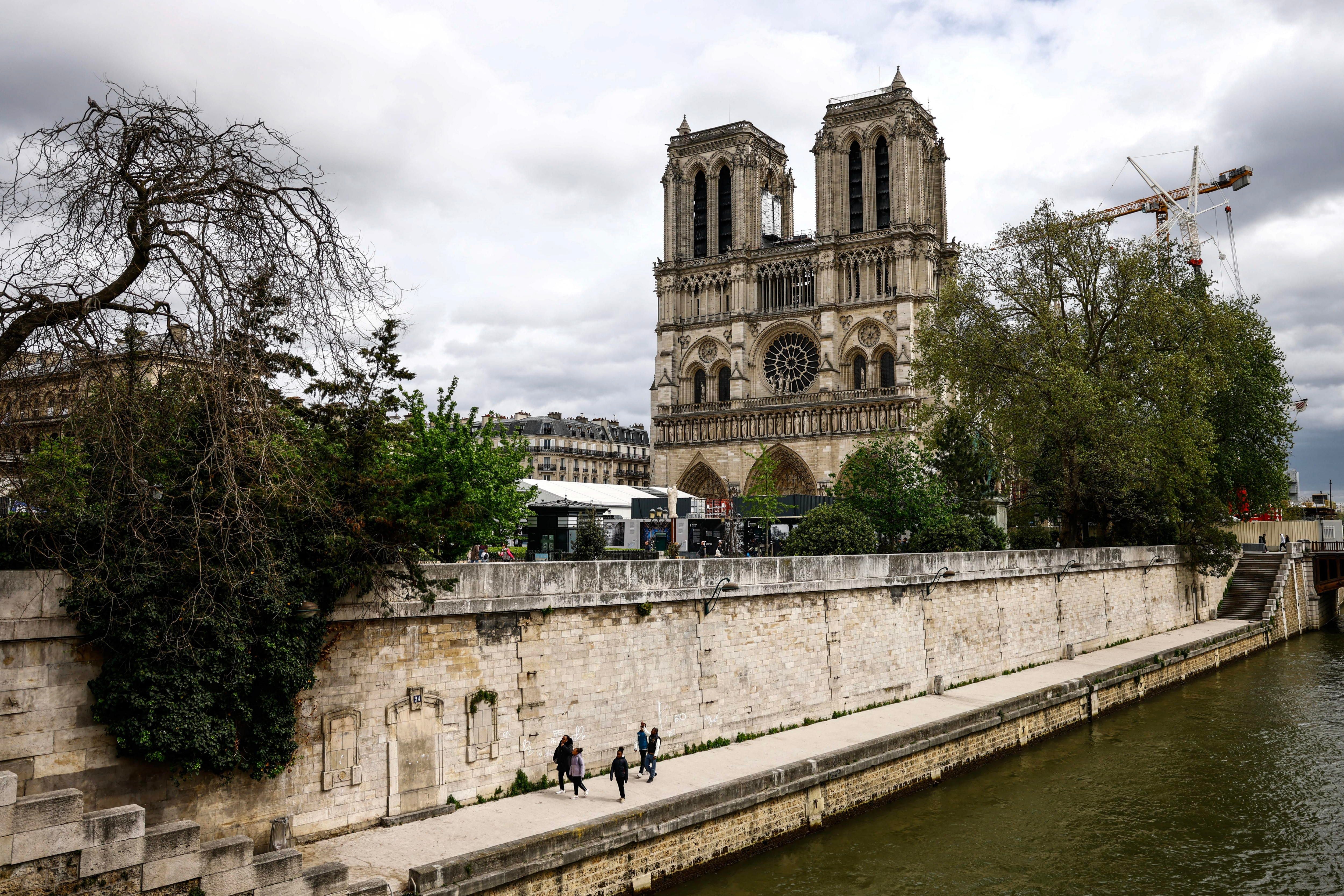 Paris (France), 15/04/2024.- People walk on the bank of the Seine river with the Notre-Dame Cathedral seen in the background, in Paris, France, 15 April 2024. Five years on since the collapse of the Notre-Dame cathedral's spire in a devastating fire on 15 April 2019, its reopening is scheduled for December 2024, according to Philippe Jost, president of the public body overseeing its reconstruction. (Francia) EFE/EPA/MOHAMMED BADRA
