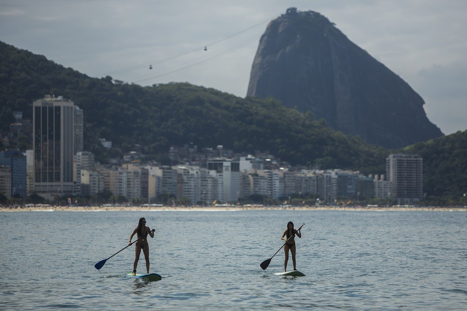 Mujeres reman sobre sus tablas en la playa de Copacabana, en Río de Janeiro, Brasil, 16 de mayo de 2021. La nueva versión de Anitta del clásico de la bossa nova "La chica de Ipanema" ofrece una actualización de las mujeres de Río respecto a la original de los años 60. (AP Foto/Bruna Prado)