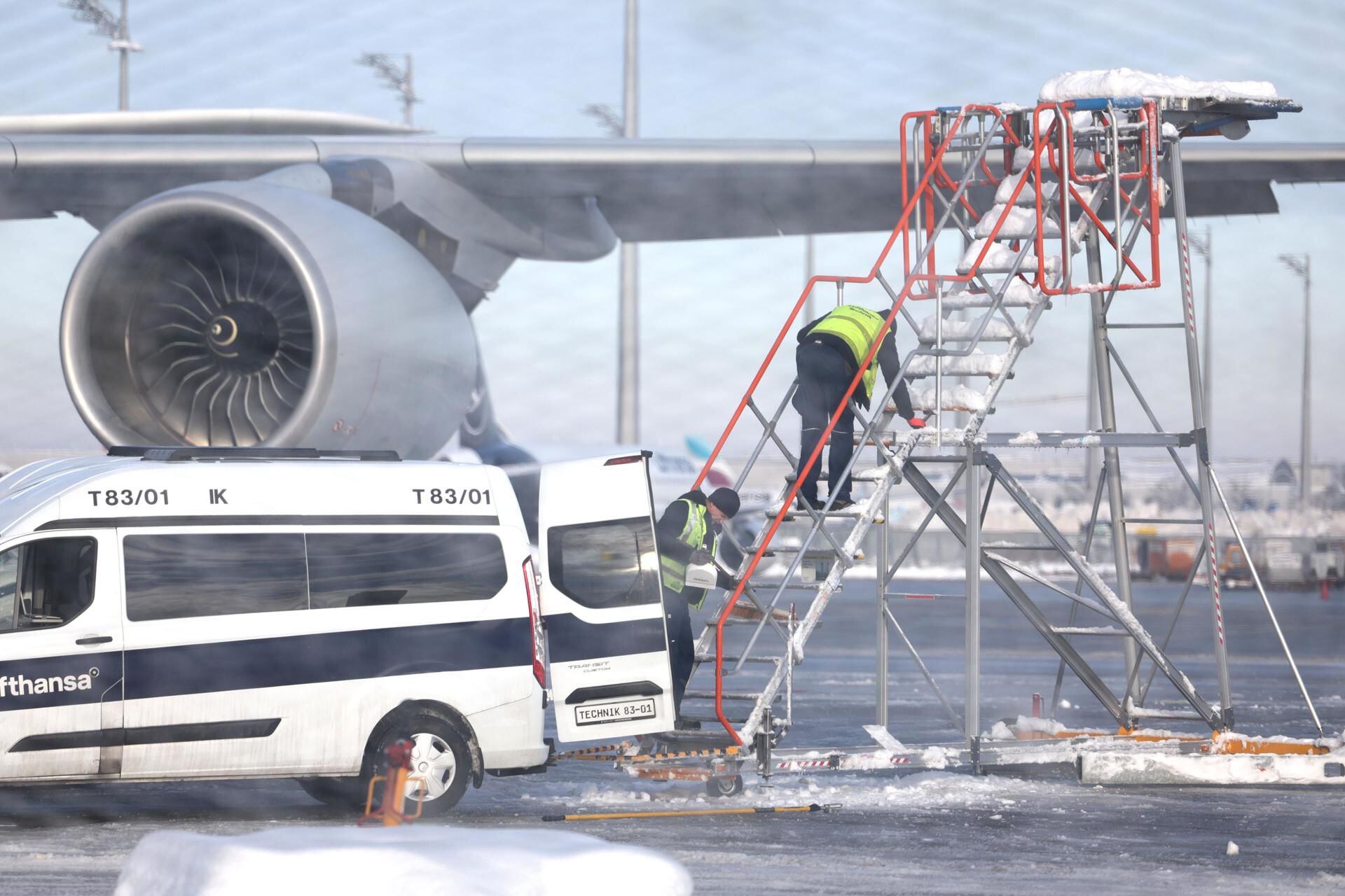Munich (Germany), 05/12/2023.- Workers remove snow from airplane stairs next to a parked Lufthansa plane at the airport in Munich, Germany, 05 December 2023. Due to overnight freezing rain conditions making 'safe flight operations impossible' in the morning at Munich Airport, there will be no take-offs and landings on 05 December until 12 noon local time, the airport announced on its website. The statement added that during the rest of the day the majority of the flights were likely to be canceled over 'safety reasons'. Flight operations at Munich Airport had been temporarily suspended over the weekend due to heavy snowfall. (Alemania) EFE/EPA/ANNA SZILAGYI
