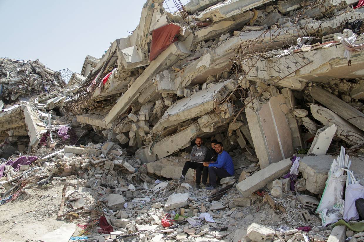 Palestinos sentados ante los escombros de un edificio residencial destruido por ataques israelíes, en medio del actual conflicto entre Israel y Hamás, en el norte de la Franja de Gaza. 22 de abril de 2024. REUTERS/Mahmoud Issa.