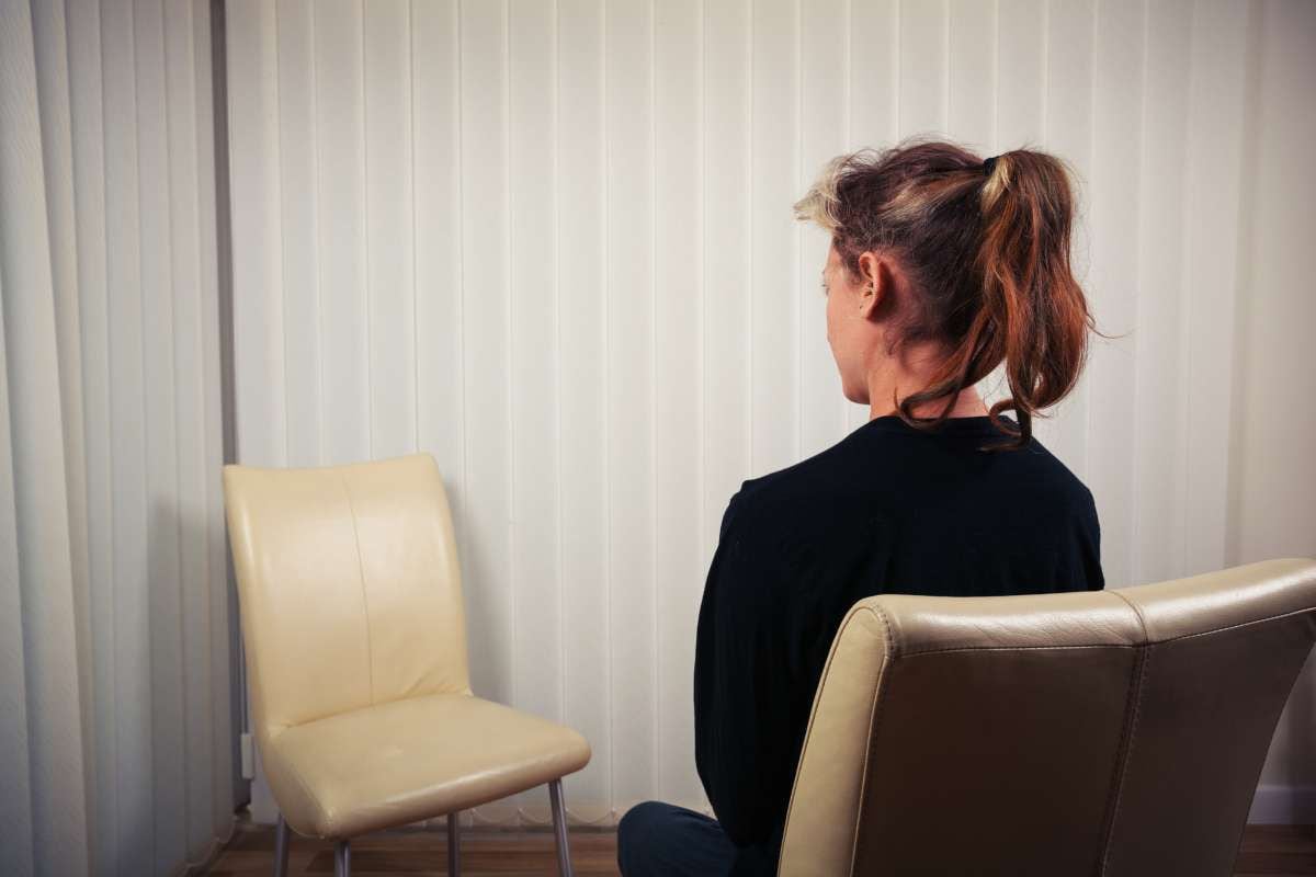 A woman is sitting on a chair and is waiting to see her doctor or therapist