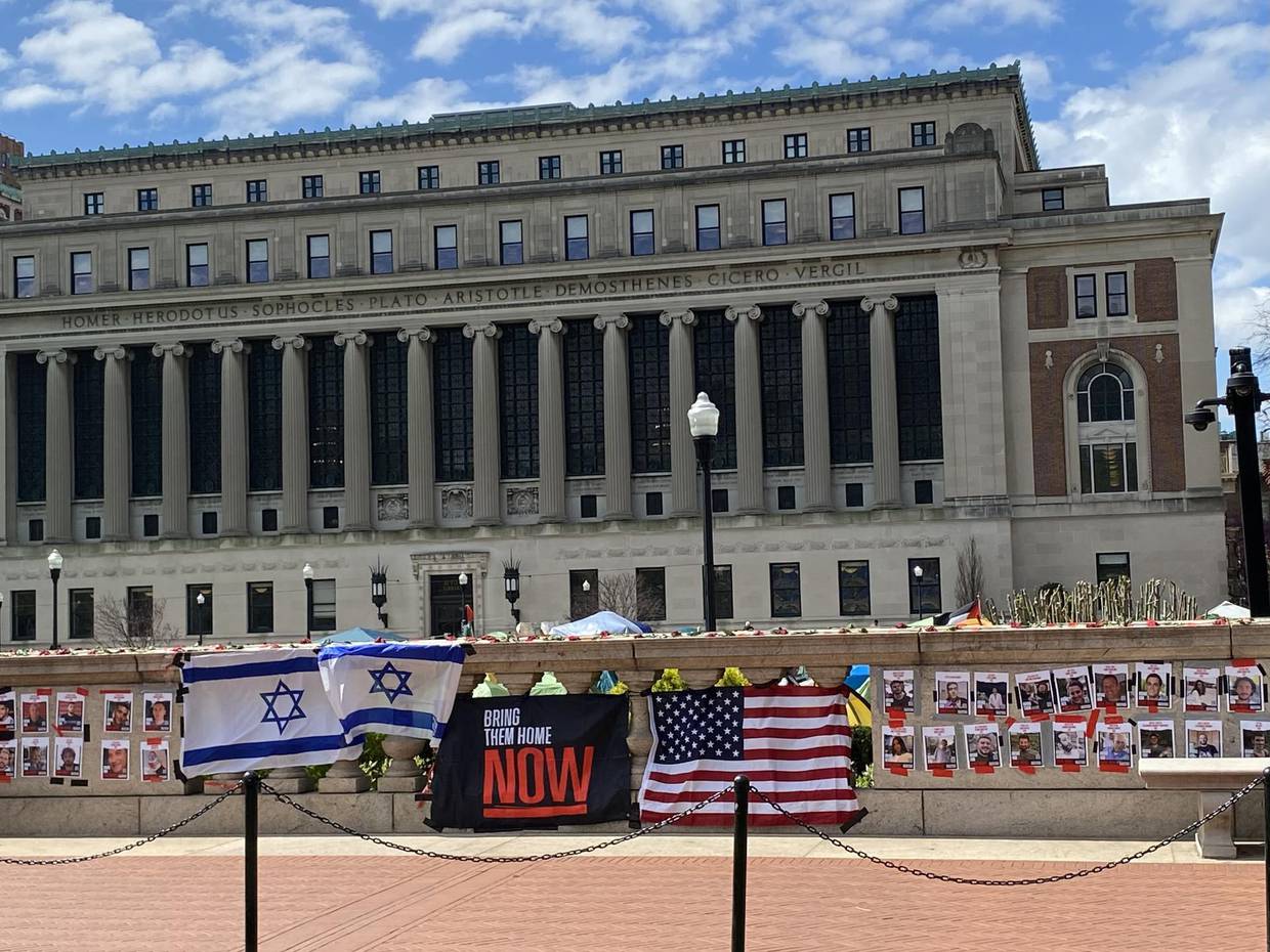 Fotografía cedida por Eva Martin donde se muestra una pared con fotos de rehenes israelíes y dos banderas, la de Israel y la estadounidense, colocadas este jueves frente al campamento de los alumnos propalestinos en la Universidad de Columbia ubicada en el Alto Manhattan en Nueva York (EE.UU.).