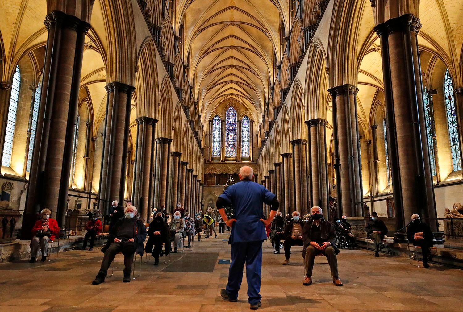 Un miembro del personal médico organiza a la gente que espera ser vacunada contra el COVID-19 en la catedral de Salisbury, Inglaterra, el 20 de enero del 2021. (AP Photo/Frank Augstein)