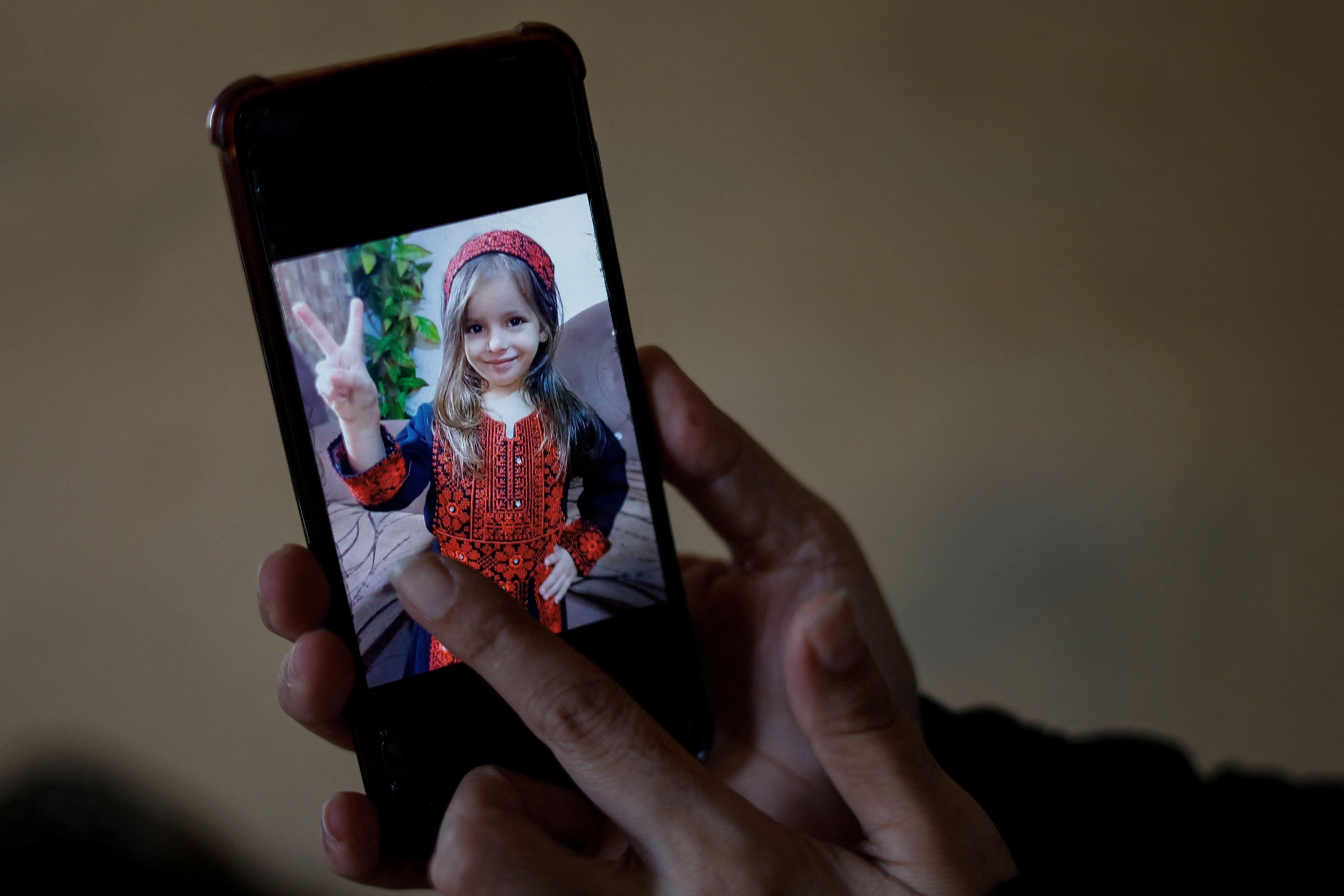 La palestina Inas Abu Maamar, de 36 años, cuya foto abrazando el cuerpo de su sobrina Saly, de 5 años, muerta en un ataque aéreo israelí, se hizo viral en medios locales e internacionales, muestra la foto de Saly en un teléfono móvil, en Khan Younis, en el sur de la Franja de Gaza, el 26 de octubre de 2023
   REUTERS/Mohammed Salem