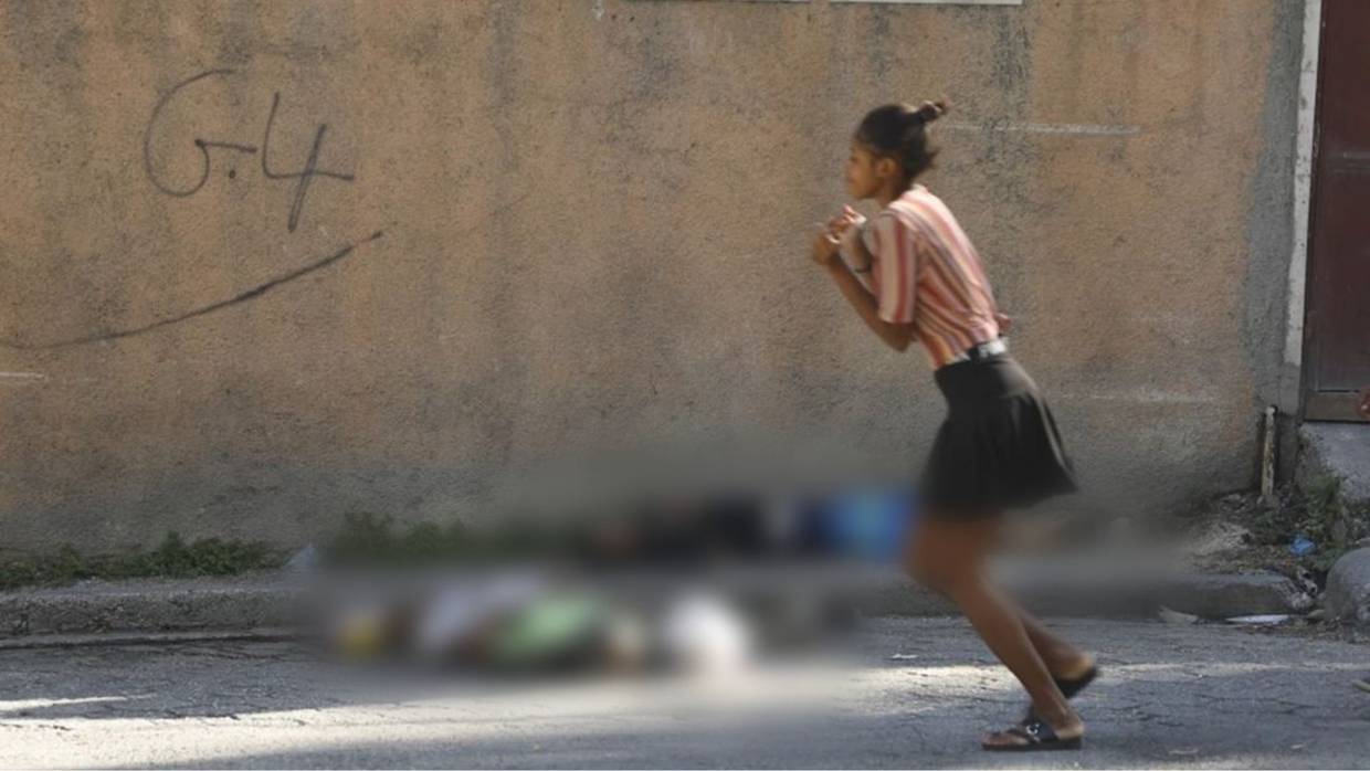 Una mujer pasa junto a los cuerpos de dos hombres asesinados por agresores desconocidos en Puerto Príncipe, Haití. Foto: AP