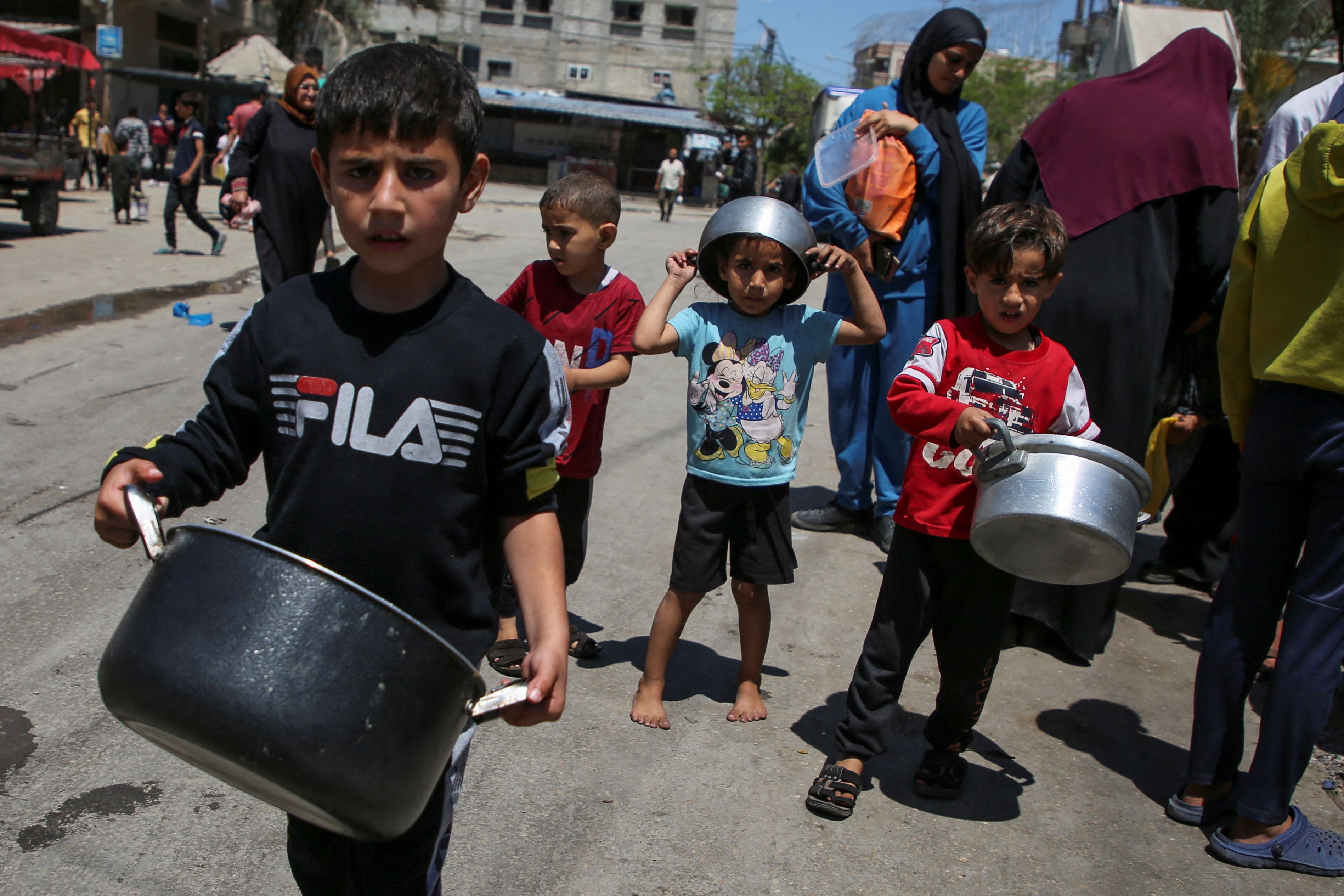Niños palestinos que llevan ollas esperan recibir comida de una cocina benéfica, en medio de la escasez de suministros de ayuda, después de que las fuerzas israelíes lanzaran una operación terrestre y aérea en la parte oriental de Rafah, mientras continúa el conflicto entre Israel y Hamás, en Rafah, en el sur de la Franja de Gaza, el 8 de mayo de 2024. REUTERS/Hatem Khaled