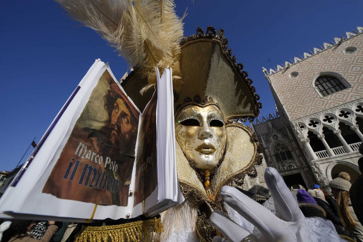 Un hombre, ataviado con una máscara, sostiene una réplica de “Los viajes de Marco Polo”, que relatan los viajes del explorador por Asia, durante el Carnaval en Venecia, Italia.