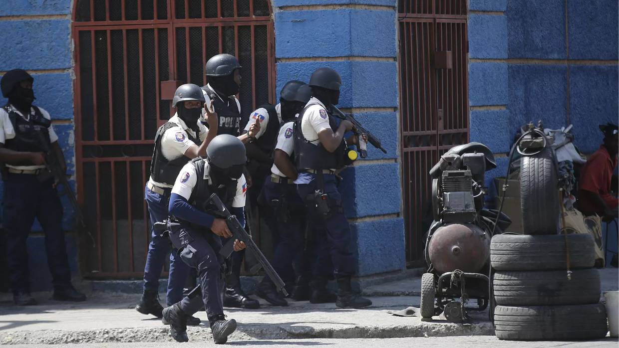 Elementos de la Policía Nacional de Haití cubriendose del fuego enemigo