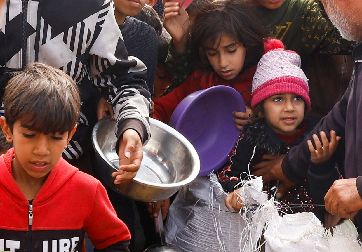 Niños palestinos desplazados esperan para recibir comida gratis en un campamento, en medio de la escasez de alimentos en Rafah, en el sur de la Franja de Gaza. 27 de febrero de 2024. REUTERS/Ibraheem Abu Mustafa