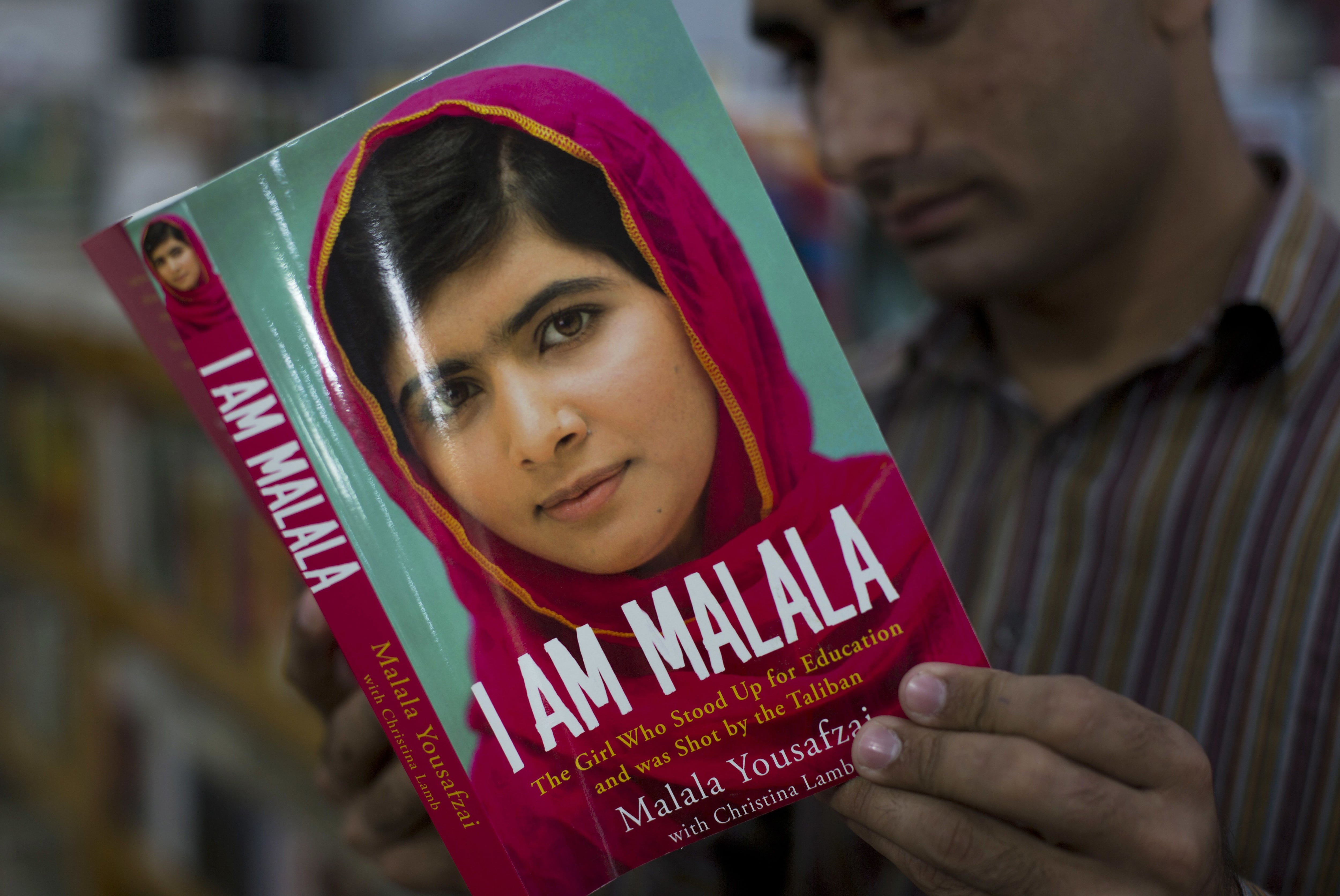 FILE - In this Friday, Oct. 10, 2014 file photo, a Pakistani customer reads the book written by Malala Yousafzai, who survived a Taliban attack, in Islamabad, Pakistan. Nobel Peace Prize winner Malala returned to Pakistan early Thursday, March 29, 2018 for the first time since she was shot in 2012 by Taliban militants angered at her championing of education for girls. (AP Photo/B.K. Bangash, file)