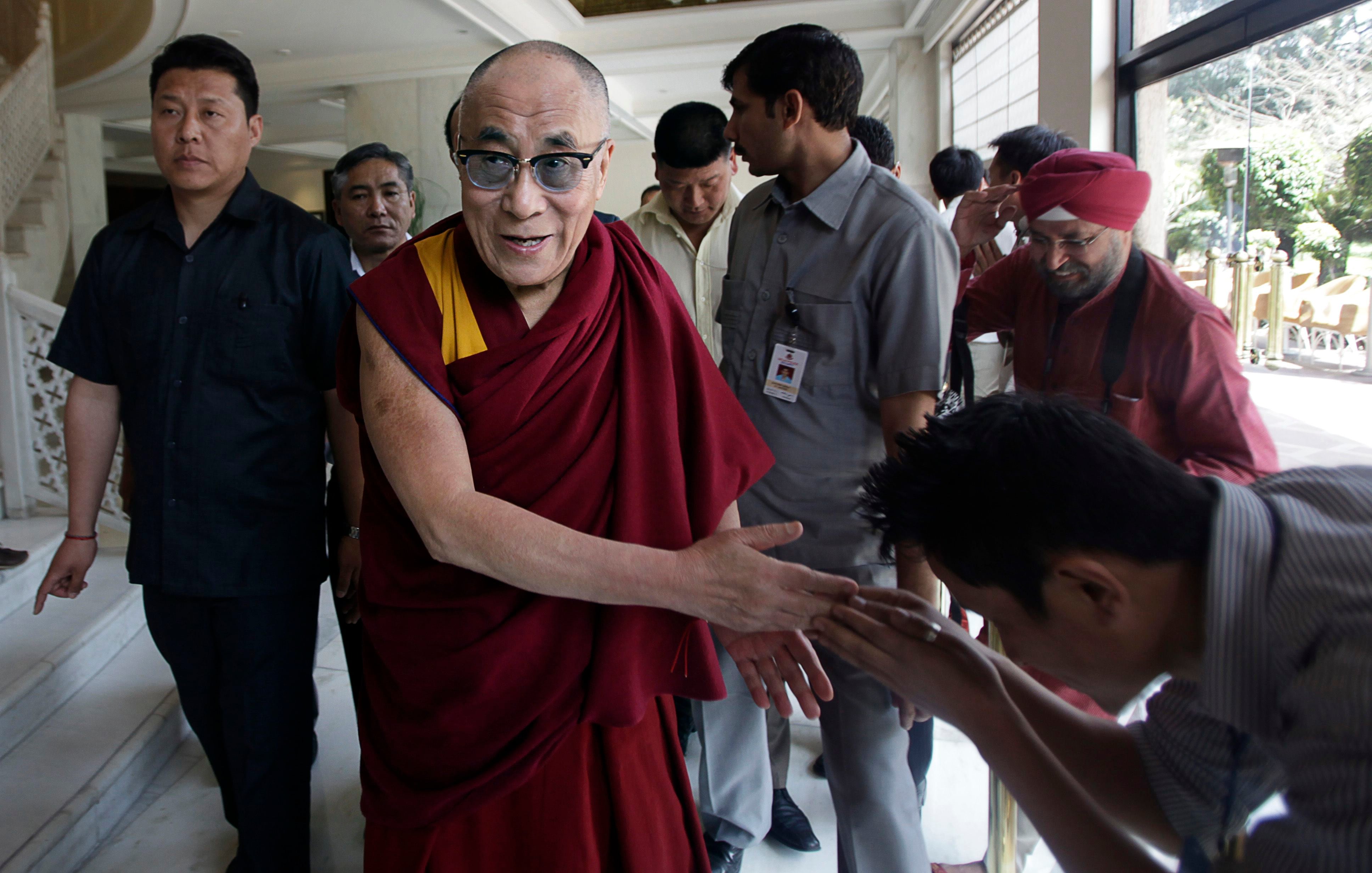 Tibetan spiritual leader the Dalai Lama greets a waiting Tibetan, on his way to deliver spiritual teachings to a gathering, in New Delhi, India, Friday, March 23, 2012.  (AP Photo/ Manish Swarup)