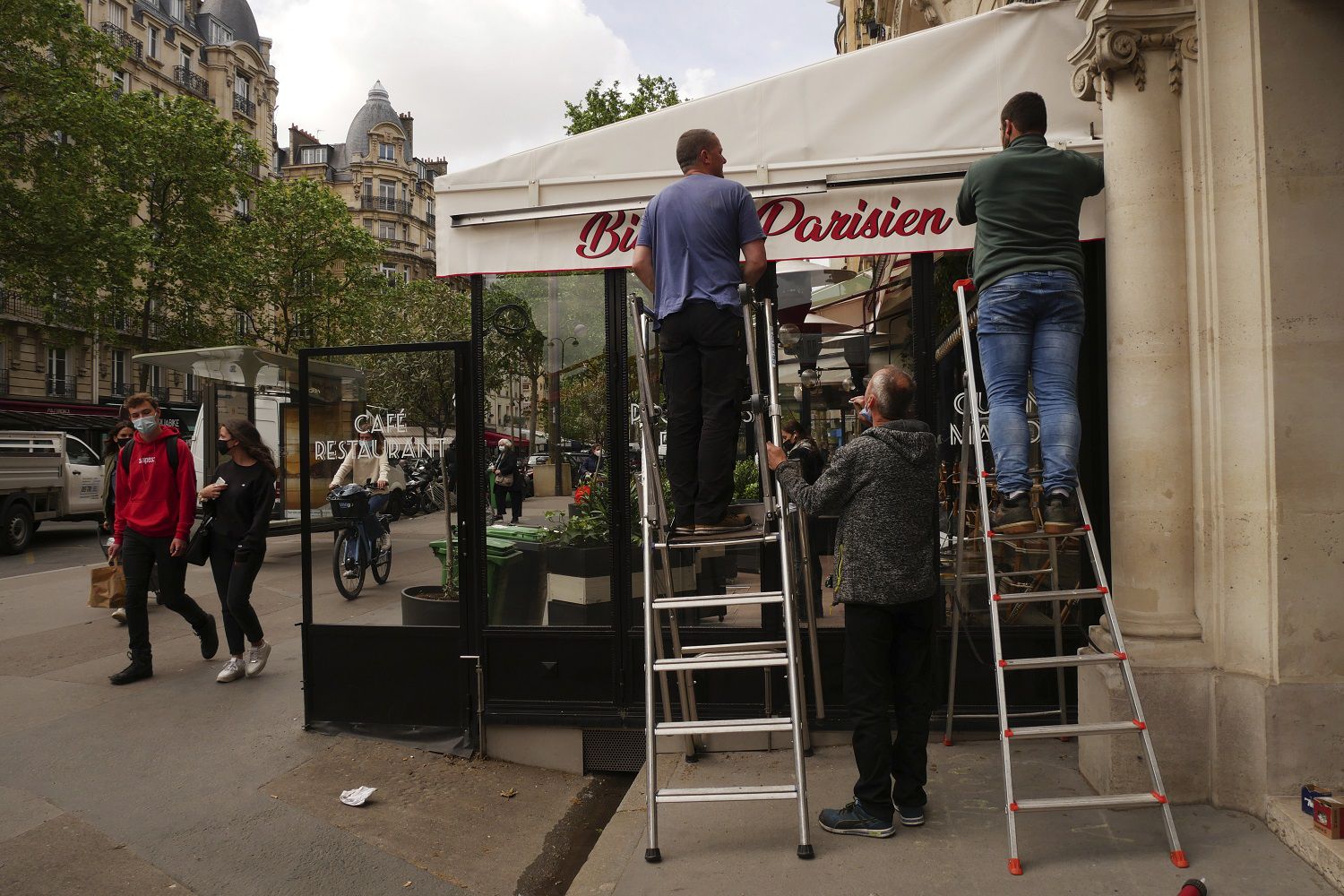 Operarios reparan el toldo de la terraza de un restaurante, antes de su reapertura, en París, el 18 de mayo de 2021. (AP Foto/Thibault Camus)