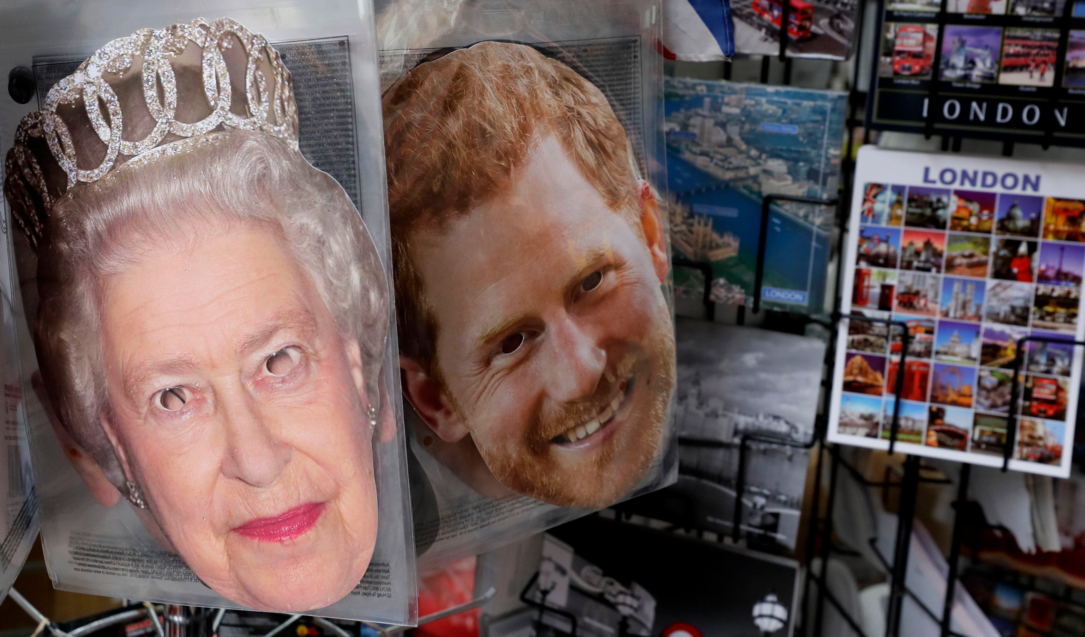 Máscaras de fiesta de la reina Isabel II y el príncipe Enrique cuelgan afuera de una tienda de souvenir en Londres el martes 14 de enero del 2020. (AP Foto/Kirsty Wigglesworth)