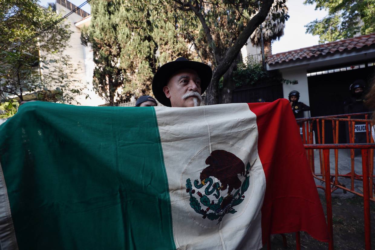 MEX3645. CIUDAD DE MÉXICO (MÉXICO), 06/04/2024.- Un hombre sostiene la bandera de México durante una protesta afuera de la Embajada de Ecuador este sábado, en la Ciudad de México (México). EFE/Sáshenka Gutiérrez