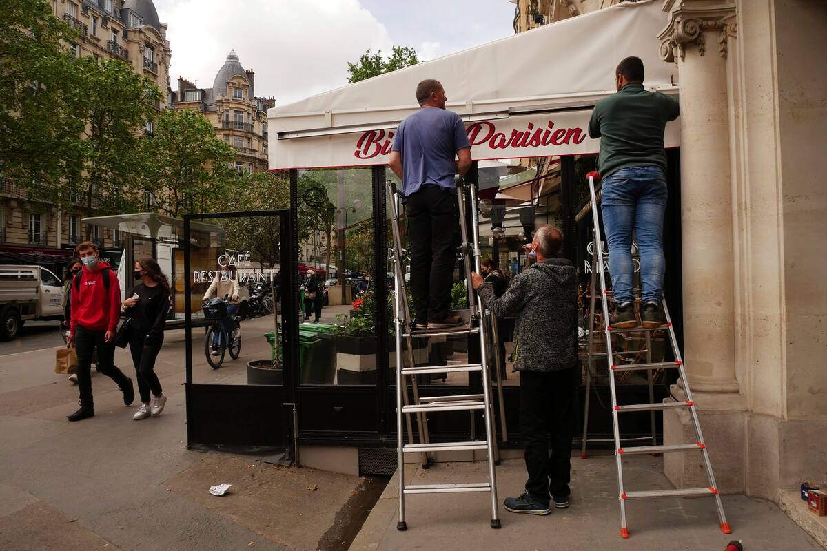 Operarios reparan el toldo de la terraza de un restaurante, antes de su reapertura, en París, el 18 de mayo de 2021. (AP Foto/Thibault Camus)