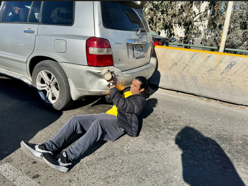 Desde la fila en la Garita de San Ysidro, Norberto Íñiguez se gana la vida reparando golpes en los autos mientras los conductores esperan cruzar la frontera. Foto: Carlos Cruz