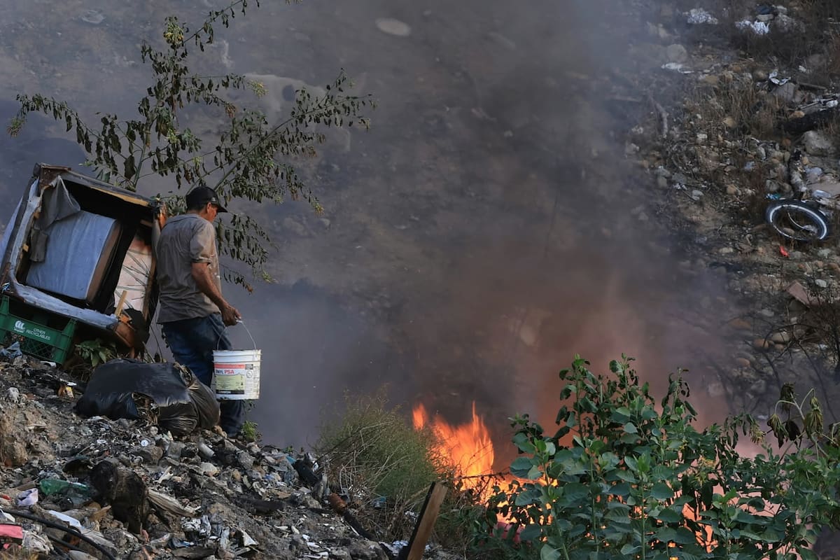 Hombre en situación de calle apaga con cubetas incendio en basurero clandestino de Tijuana
