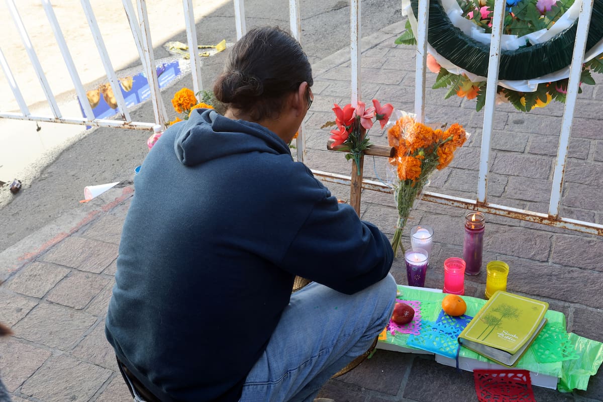 Una joven deja una veladora junto a la reja de seguridad, a unos metros  de la tienda Waldo’s. FOTO: ELEAZAR ESCOBAR