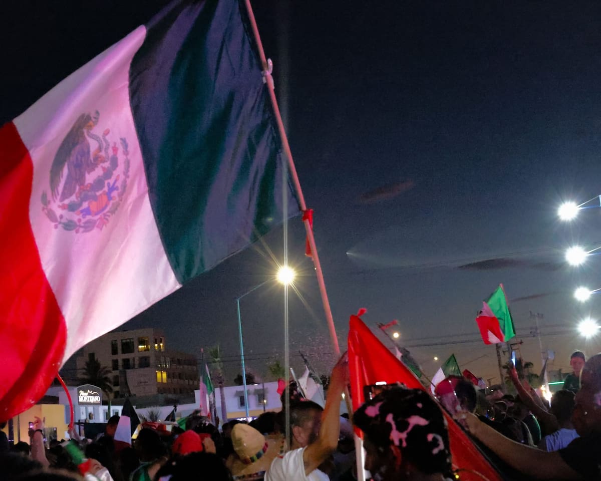 Aficionados celebran el triunfo de México en el Mundial mientras el lanzamiento de un cohete Falcon 9 de SpaceX cruza el cielo de Mexicali. (Javier Gallegos)