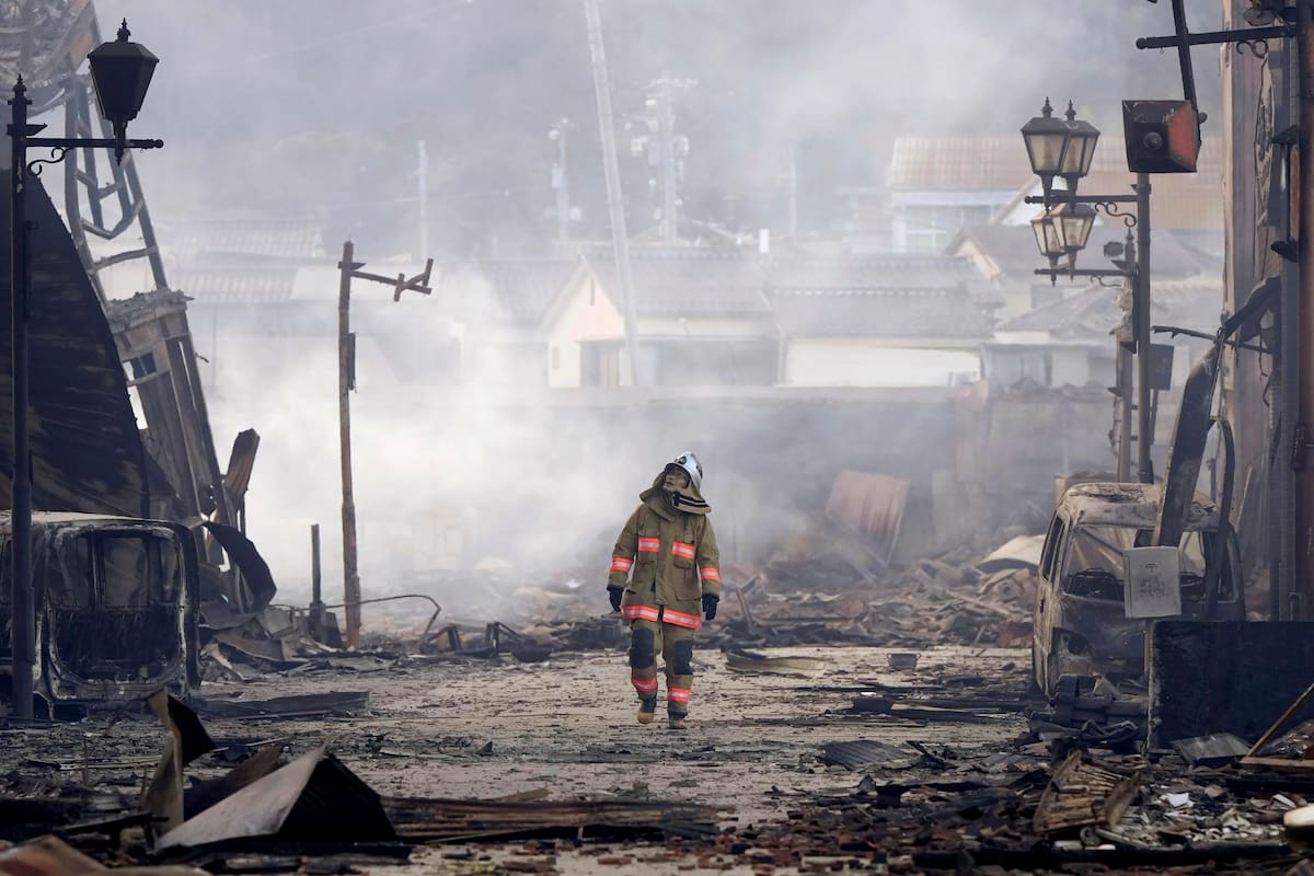 Un bombero camina entre los escombros y los restos de un incendio en un mercado, luego de un terremoto, en Wajima, en la prefectura de Ishikawa, Japón, el 2 de enero de 2024. (Kyodo News vía AP)