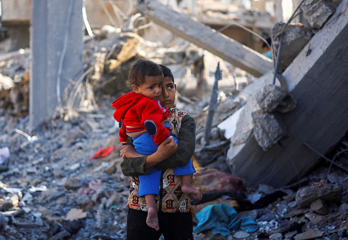 Un niño palestino con un bebé en brazos en un lugar donde hubo ataques israelíes, en medio del actual conflicto entre Israel y el grupo palestino Hamás, en Rafah, en el sur de la Franja de Gaza. 4 de diciembre de 2023. REUTERS/Mohammed Salem