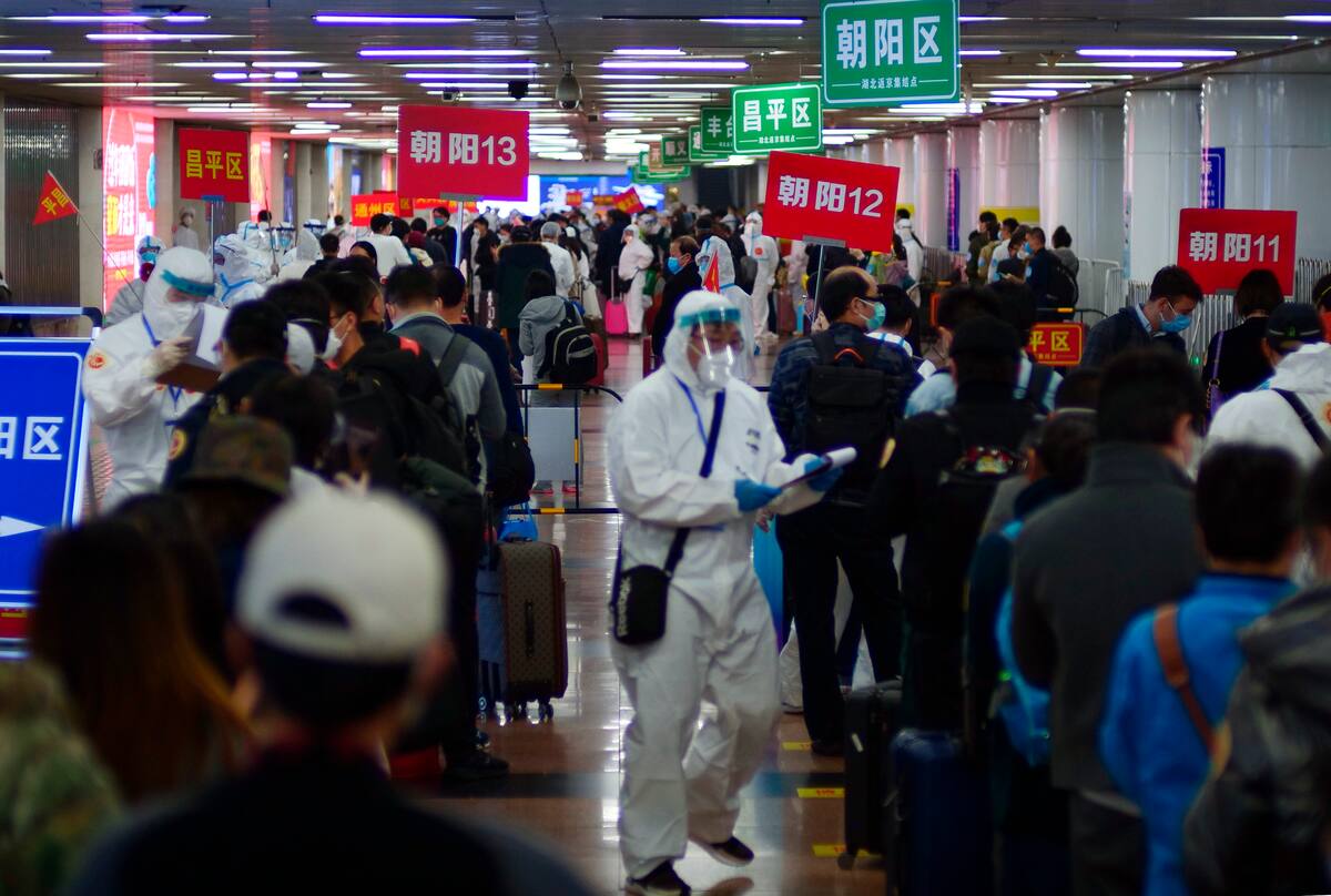 Pasajeros de Wuhan esperan en filas que señalan donde realizarán una cuarentena en Beijing, China, el 15 de abril de 2020. (AP Foto/Sam McNeil)