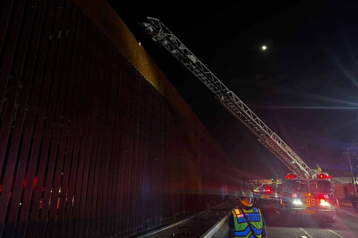 Bomberos bajan a hombre que subió hasta lo alto del cerco fronterizo en Mexicali
