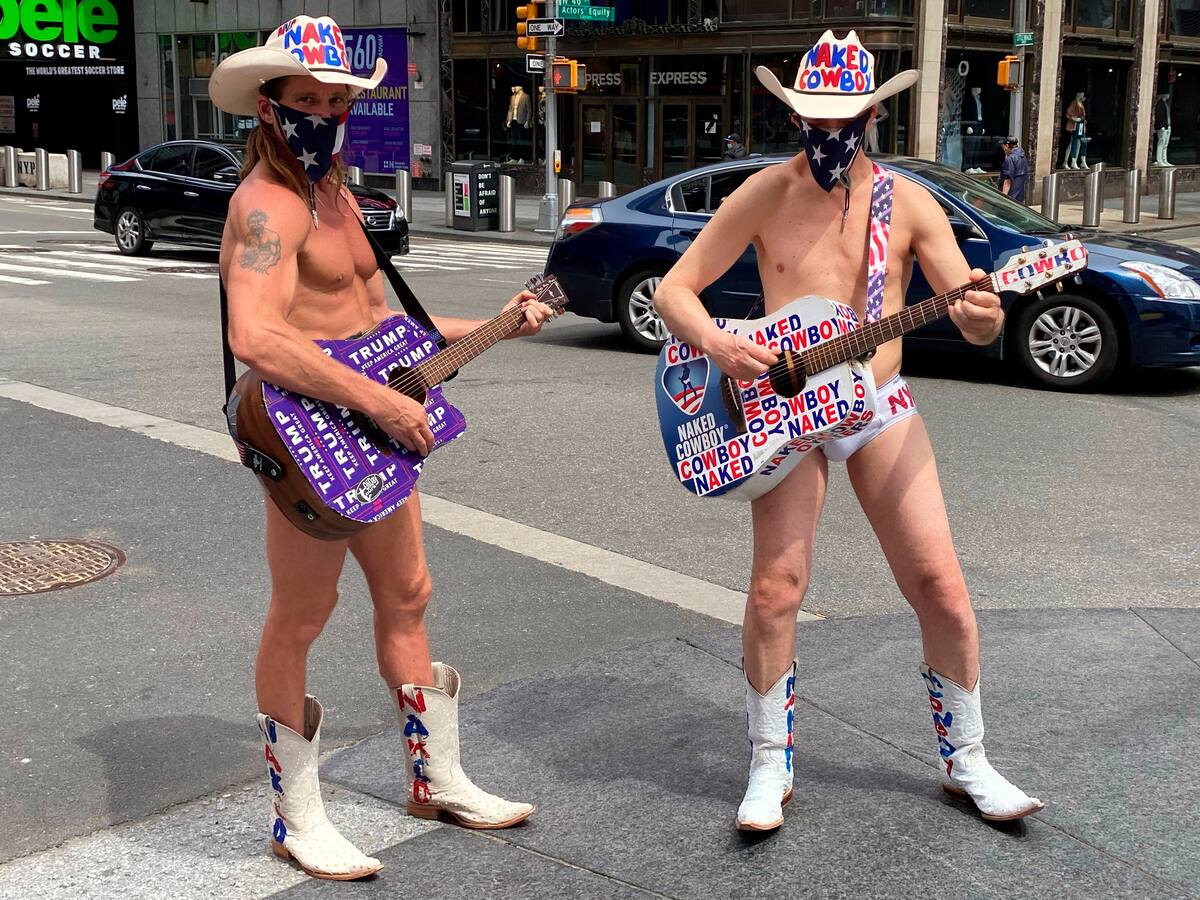 Dos personas disfrazadas como el famoso personaje de Times Square "Naked Cowboy" (Vaquero Desnudo), llevan un pañuelo tapaboca con la estrellas de la bandera nacional este fin de semana en una calle de Nueva York (EE.UU). EFE/ Carles Escolà