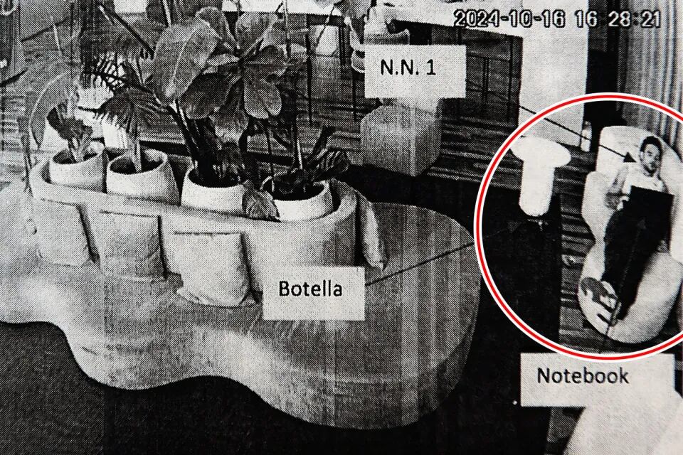 Liam en el sofá del hotel a las 4:28 p.m., con notas en la imagen que muestran botellas y su laptop.