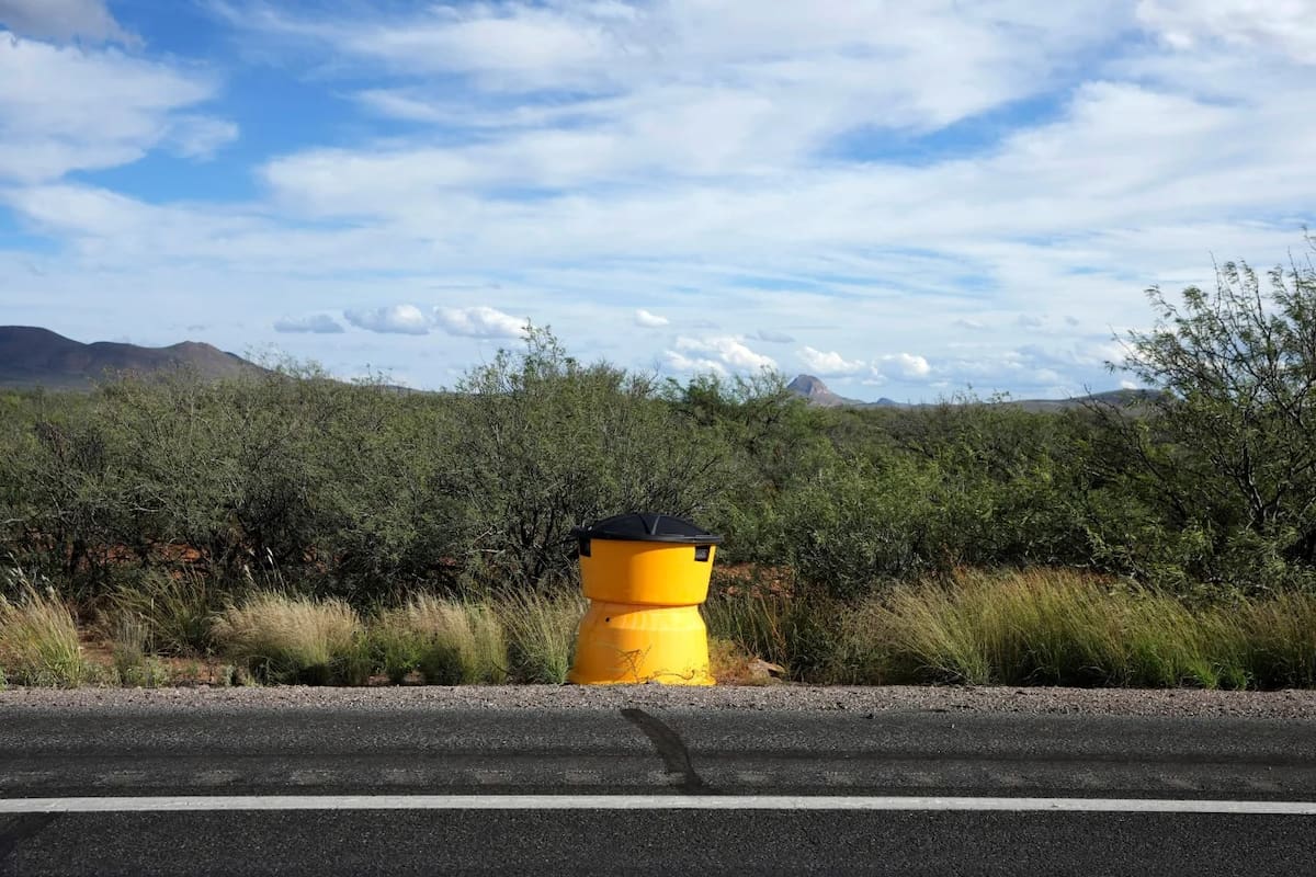 Un lector de matrículas utilizado por la Patrulla Fronteriza de Estados Unidos está oculto en un barril de arena junto a la carretera estatal 80, el jueves 23 de octubre de 2025, en Douglas, Arizona. | Crédito: AP/Ross D. Franklin