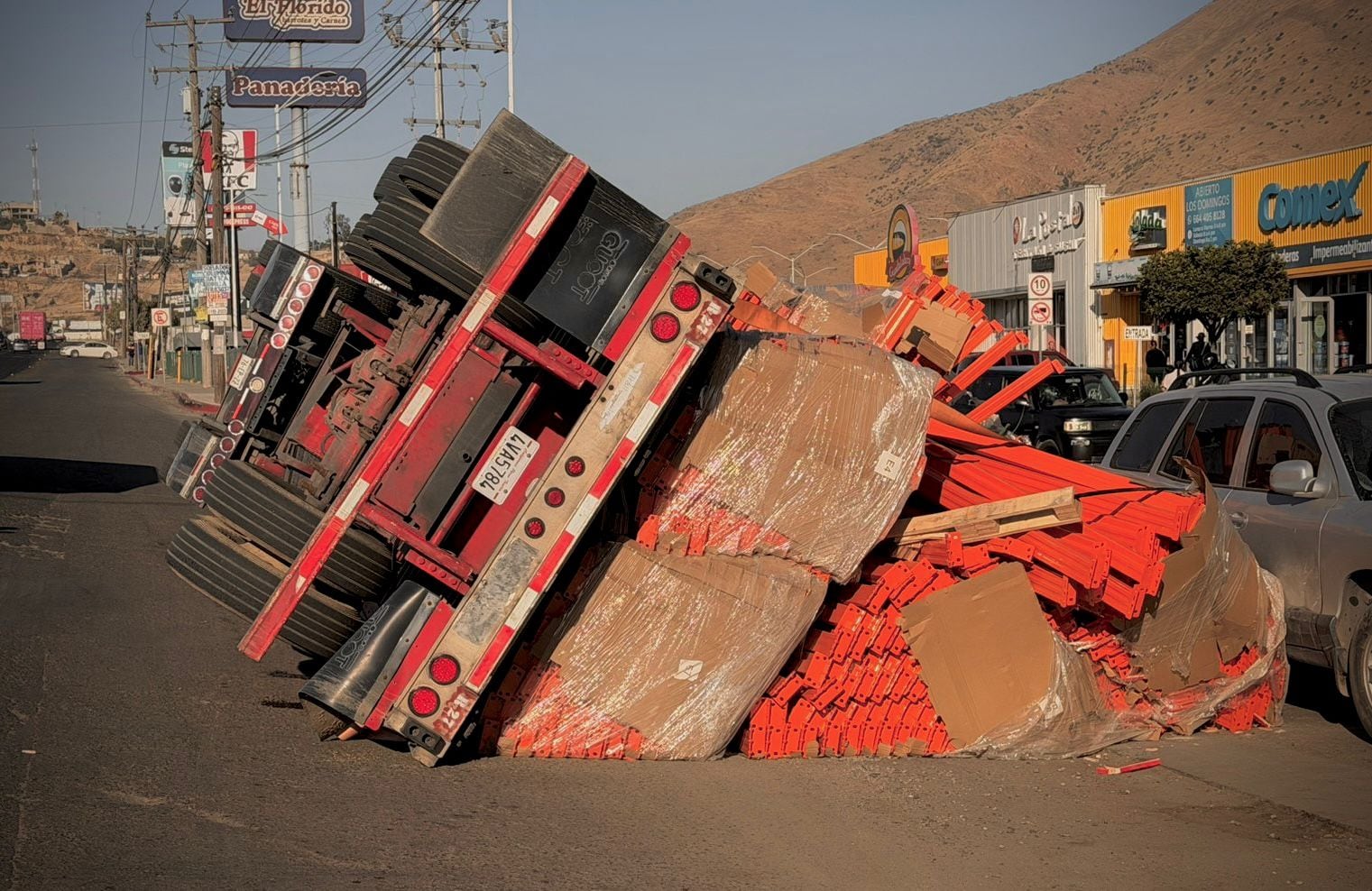 Un tráiler cargado con vigas volcó sobre la carretera libre Tijuana-Tecate, a la altura de El Refugio; el conductor resultó ileso y el accidente habría ocurrido tras perder el control al orillarse sobre un desnivel. Foto: Border Zoom