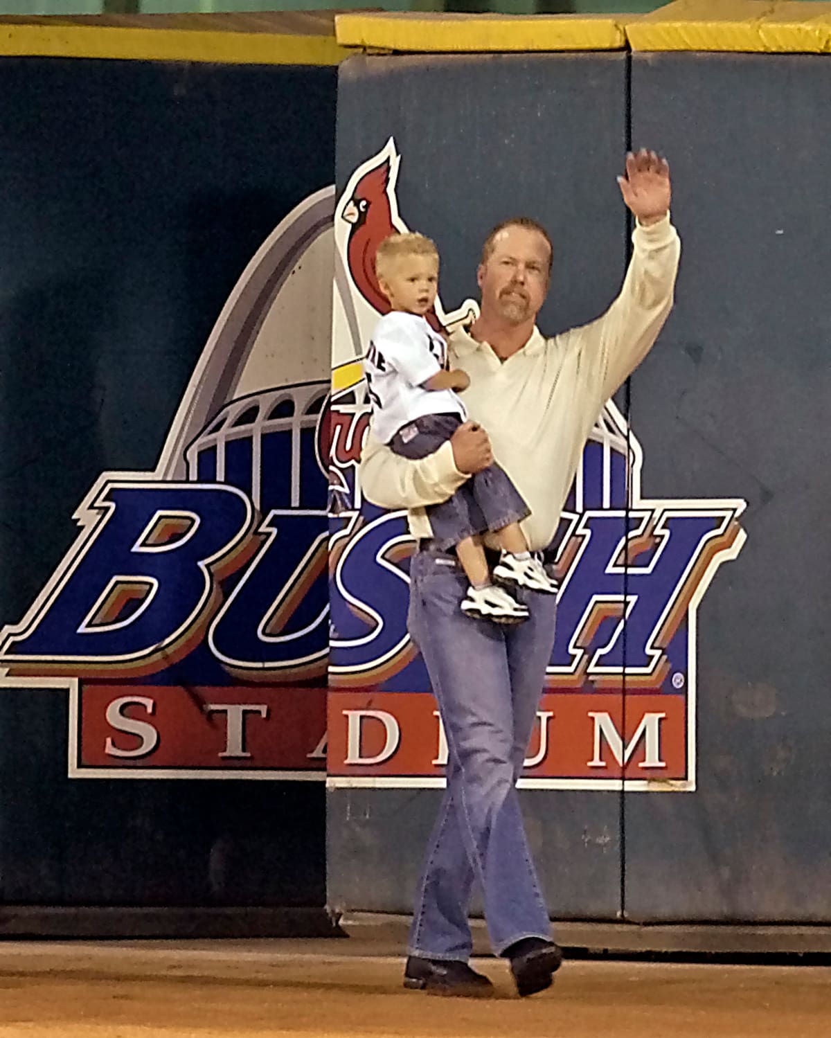 Mark McGwire entra al campo del Busch Stadium en 2005 con su hijo Max en los brazos. (AP photo/Tom Gannam)
