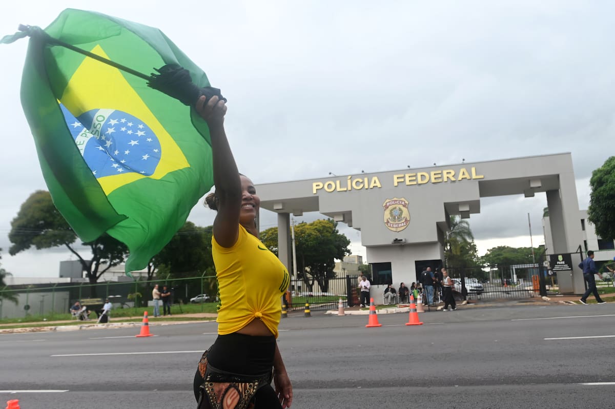 (251123) -- BRASILIA, 23 noviembre, 2025 (Xinhua) -- Una simpatizante del expresidente brasileño, Jair Bolsonaro, quien se encuentra en detención preventiva, sostiene una bandera nacional brasileña en la entrada de la Superintendencia de la Policía Federal, en Brasilia, capital de Brasil, el 23 de noviembre de 2025. La detención de Bolsonaro fue hecha efectiva por riesgo "concreto" de fuga, reveló el sábado el Supremo Tribunal Federal de Brasil. (Xinhua/Lucio Tavora) (lt) (rtg) (ah)