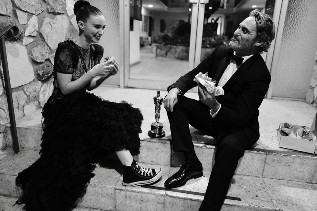 Joaquin Phoenix celebra triunfo sentado en una banqueta con hamburguesa vegana