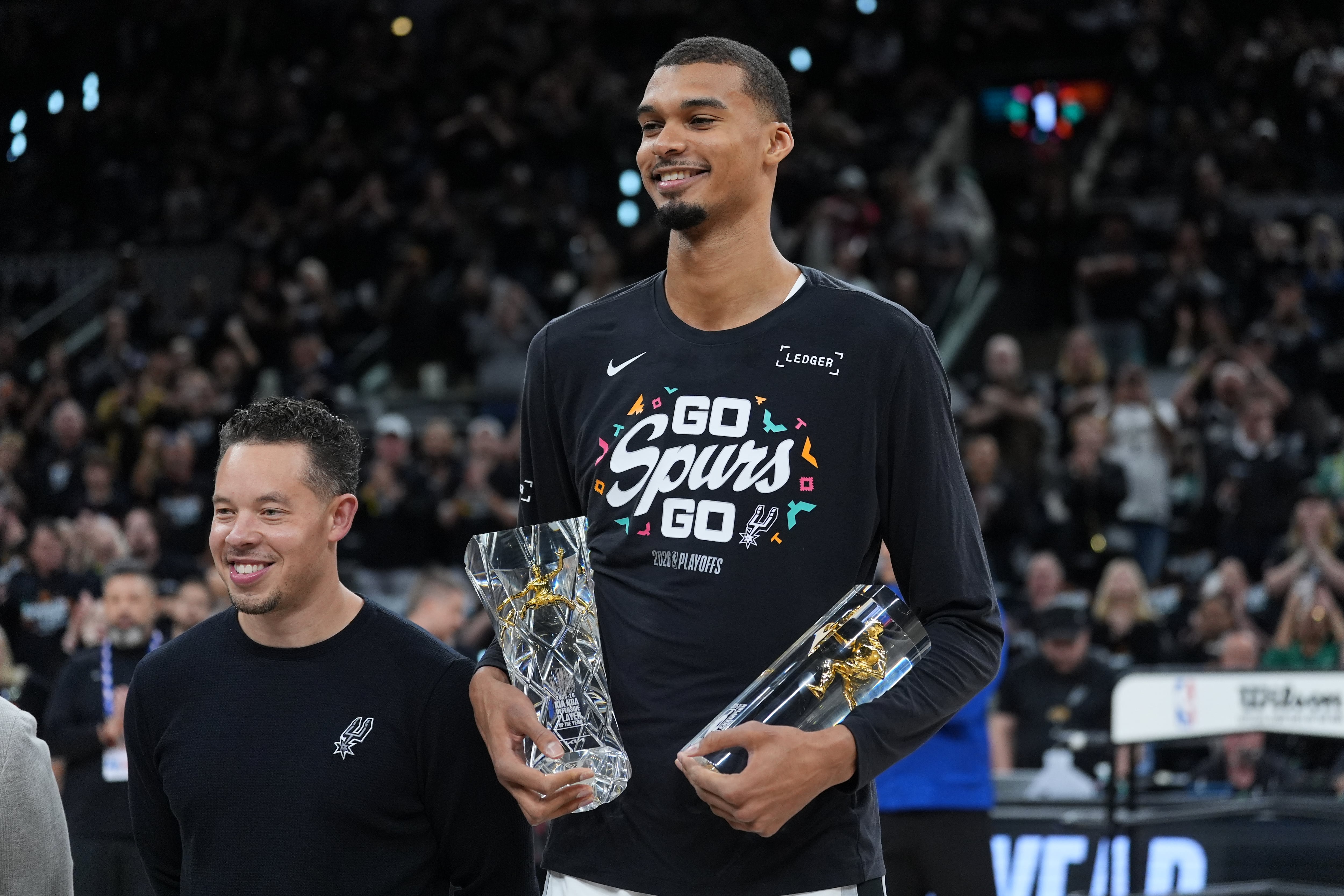 El alero de los Spurs de San Antonio Victor Wembanyama, junto al entrenador Mitch Johnson tras recibir el premio al Defensivo del Año antes del juego 2 de la primera ronda el martes 21 de abril del 2026. (AP Foto/Eric Gay)